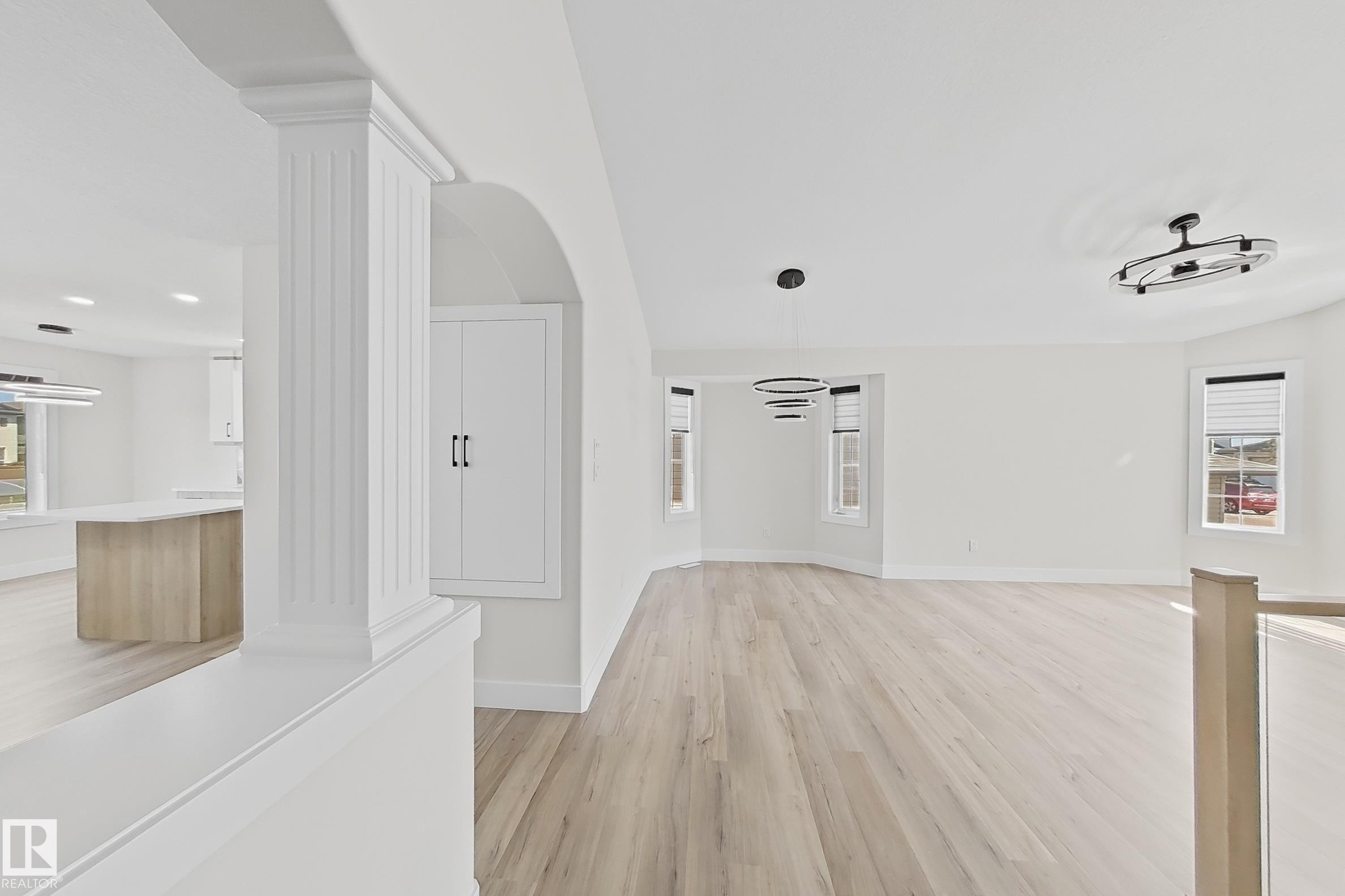 Open-concept interior featuring light wood-finish flooring, white walls, and contemporary black-finish lighting fixtures - 6144 166 Avenue, Edmonton, AB