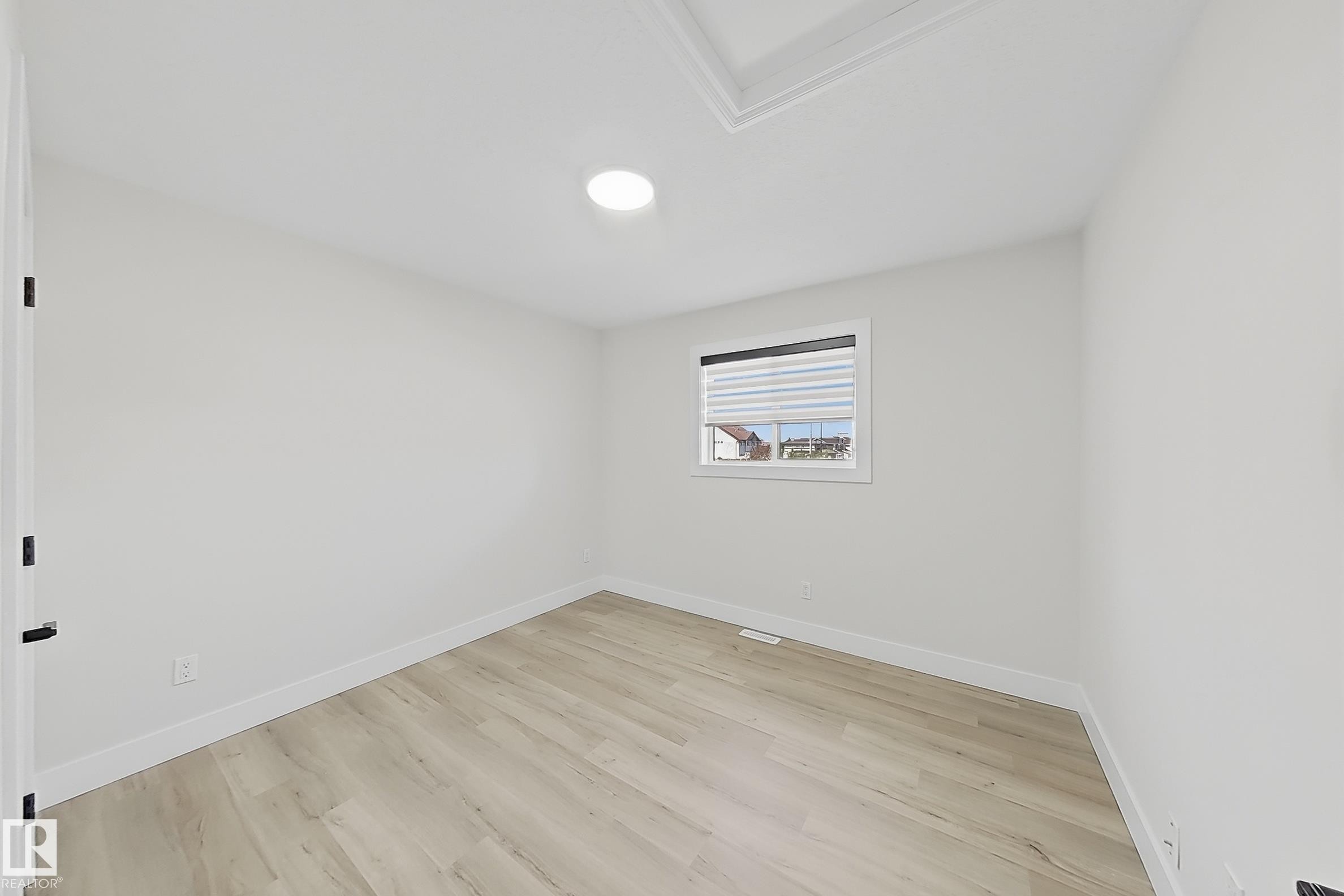 Neutral-toned interior featuring light wood-finish flooring, white walls, and a white window frame with integrated blinds - 6144 166 Avenue, Edmonton, AB
