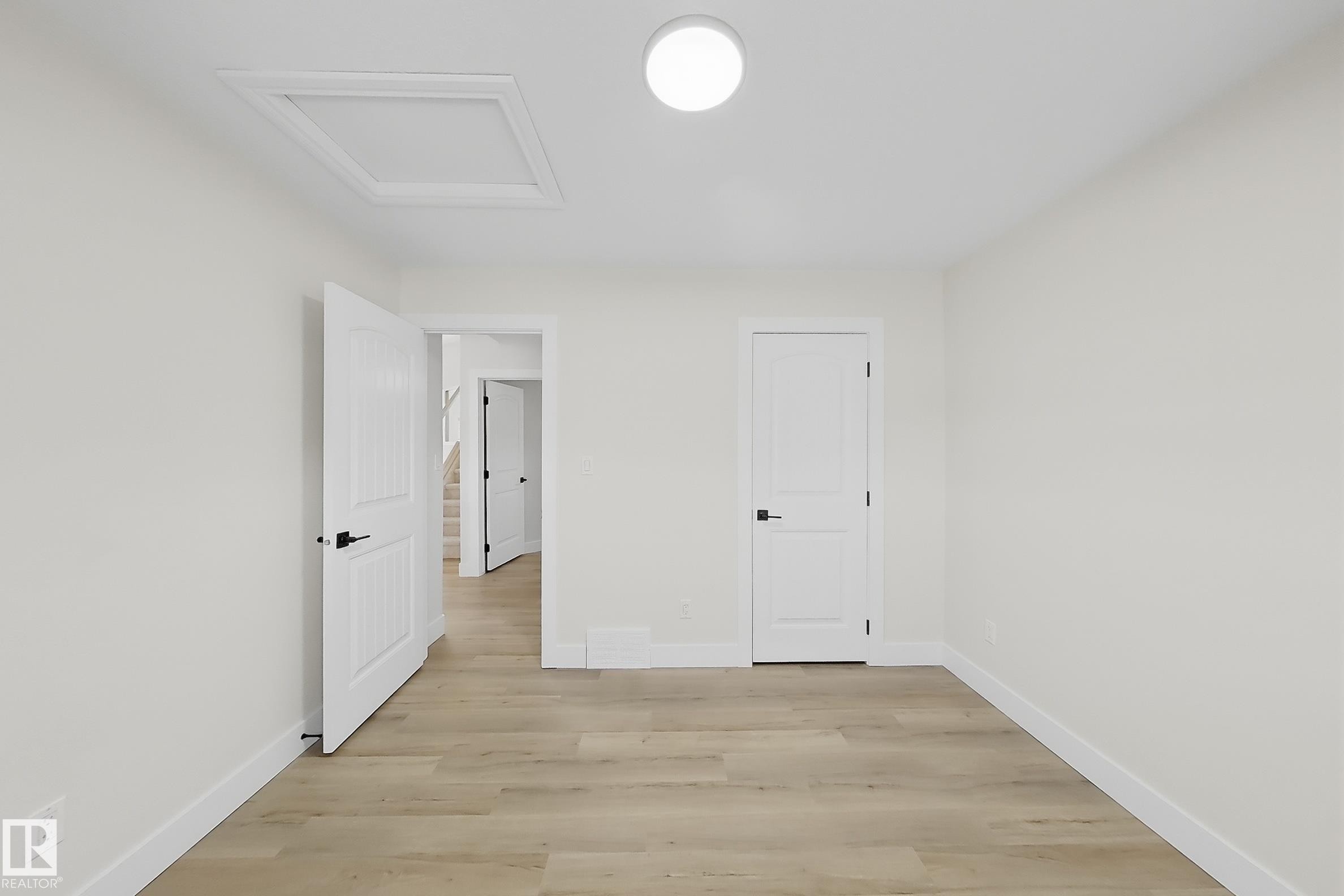 Bright room with wood-finish flooring, white walls, and a contemporary ceiling light fixture - 6144 166 Avenue, Edmonton, AB
