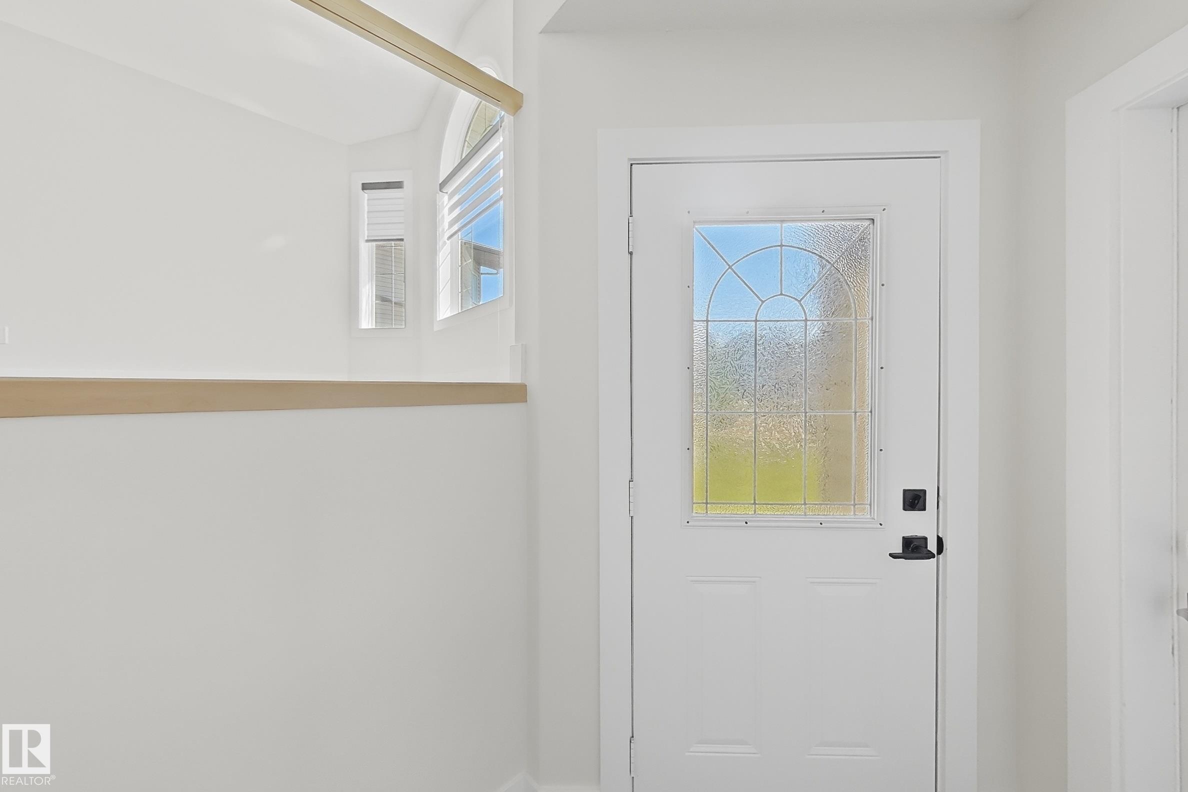 Entry door with decorative glass insert, black hardware, and light wood accent trim - 6144 166 Avenue, Edmonton, AB