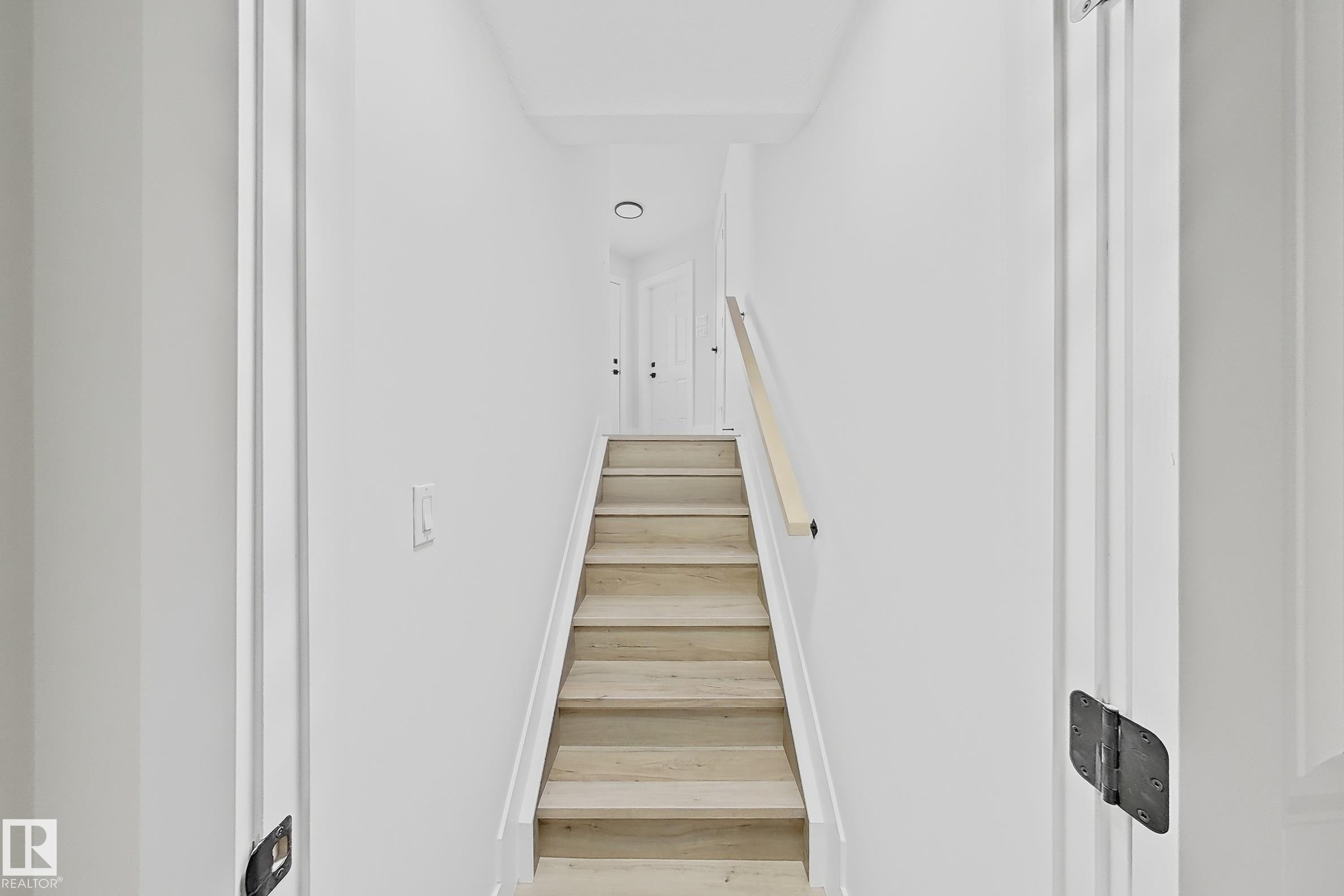 Staircase featuring wood-finish treads, a light wood handrail, and white risers - 6144 166 Avenue, Edmonton, AB