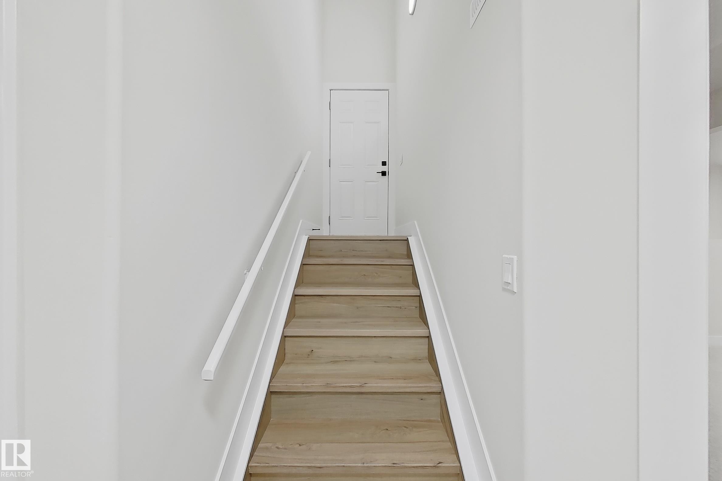 Staircase featuring wood-finish treads, a white handrail, and white risers - 6144 166 Avenue, Edmonton, AB