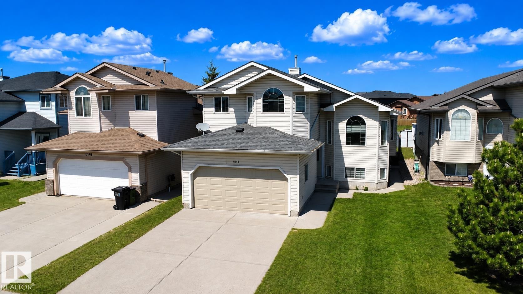 Contemporary residential exterior featuring neutral siding, arched windows, and an attached two-car garage - 6144 166 Avenue, Edmonton, AB