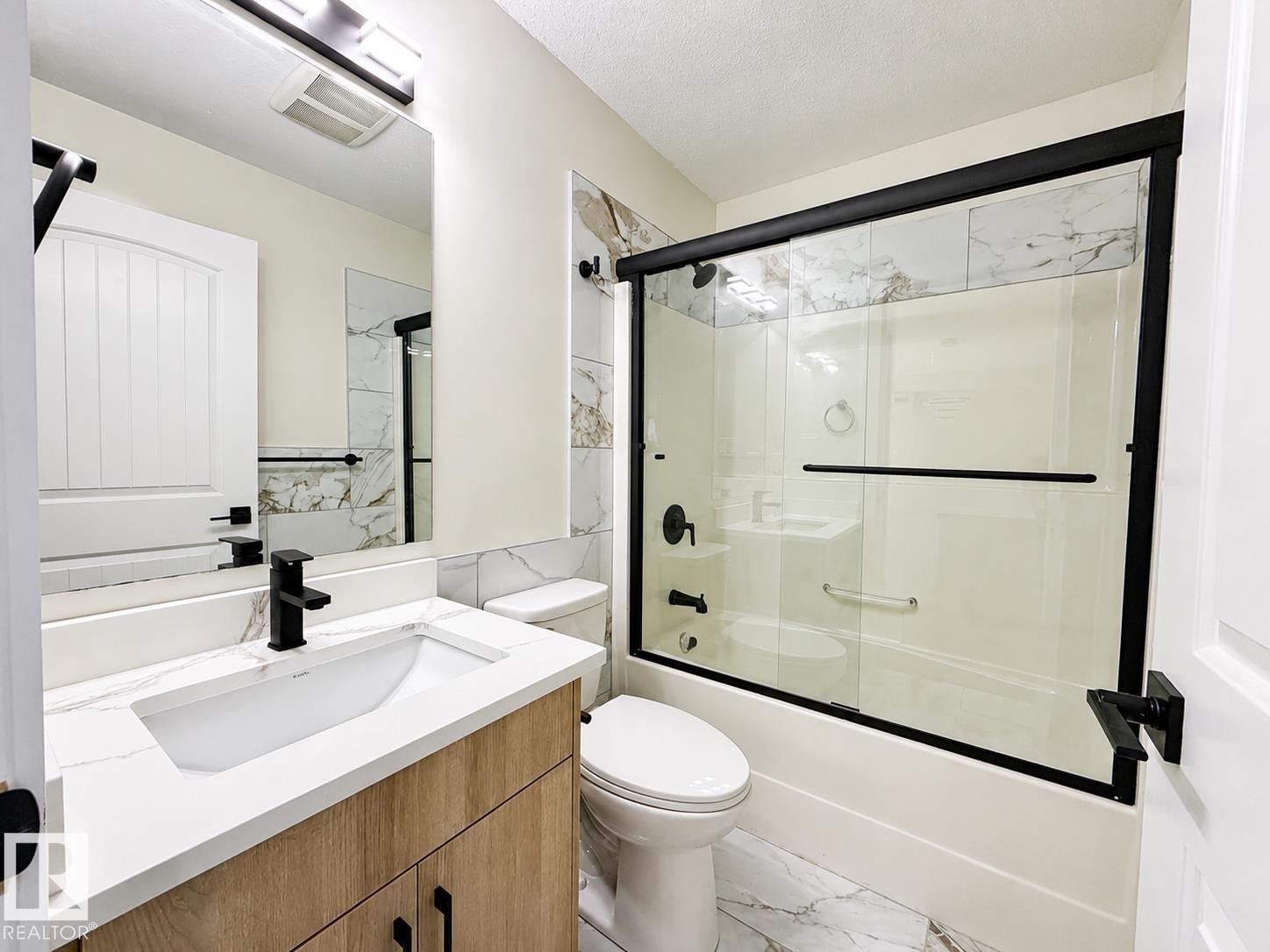 Contemporary bathroom featuring a light wood-finish vanity with a white countertop and rectangular sink - 6144 166 Avenue, Edmonton, AB