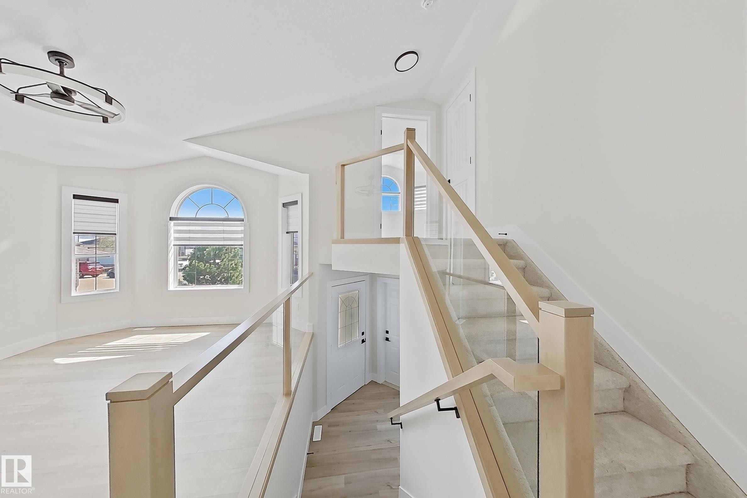 Modern interior featuring a grand staircase with glass railings and wood newel posts - 6144 166 Avenue, Edmonton, AB