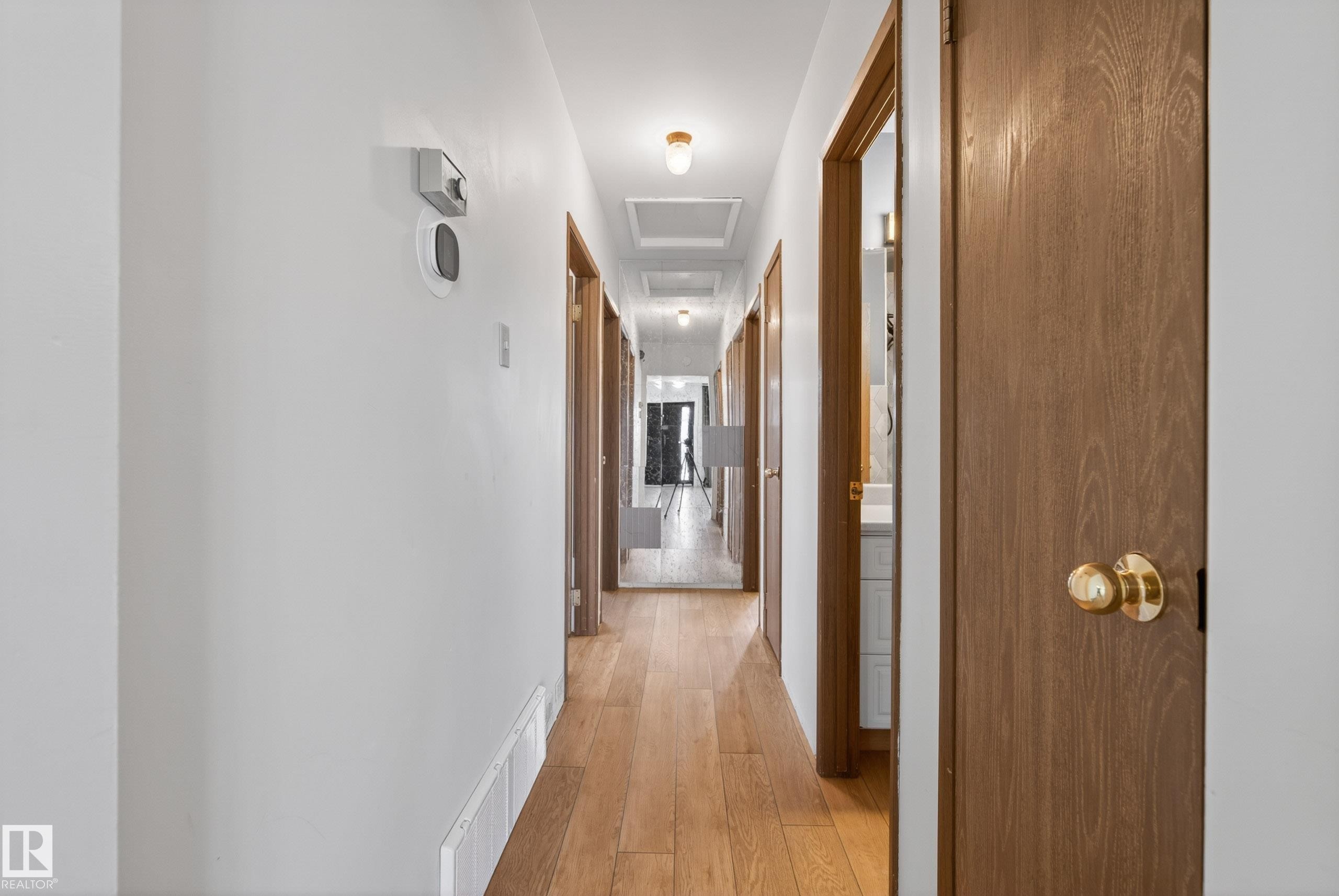 Hallway featuring wood-finish flooring, white walls, and recessed lighting - 6203 90 Avenue, Edmonton, AB