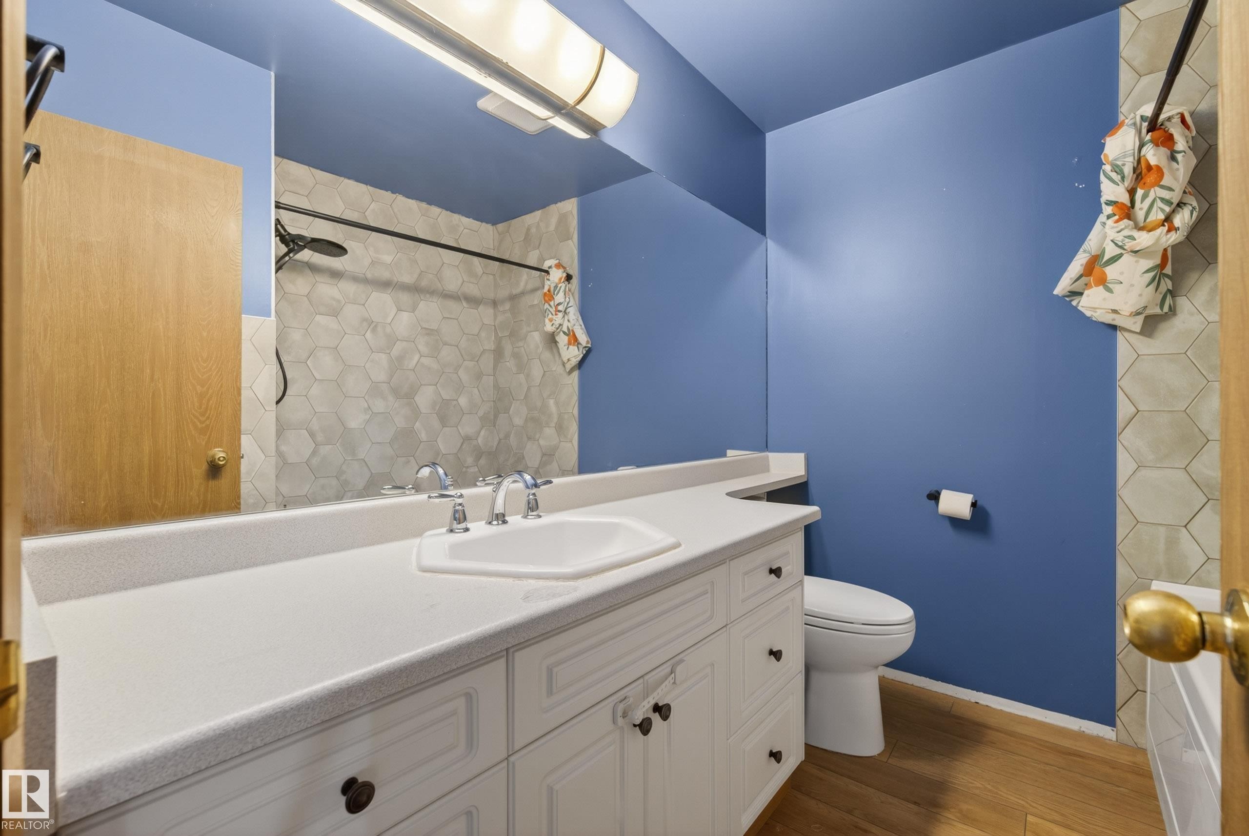 Bathroom vanity with a white countertop and integrated sink, complemented by a large wall mirror - 6203 90 Avenue, Edmonton, AB