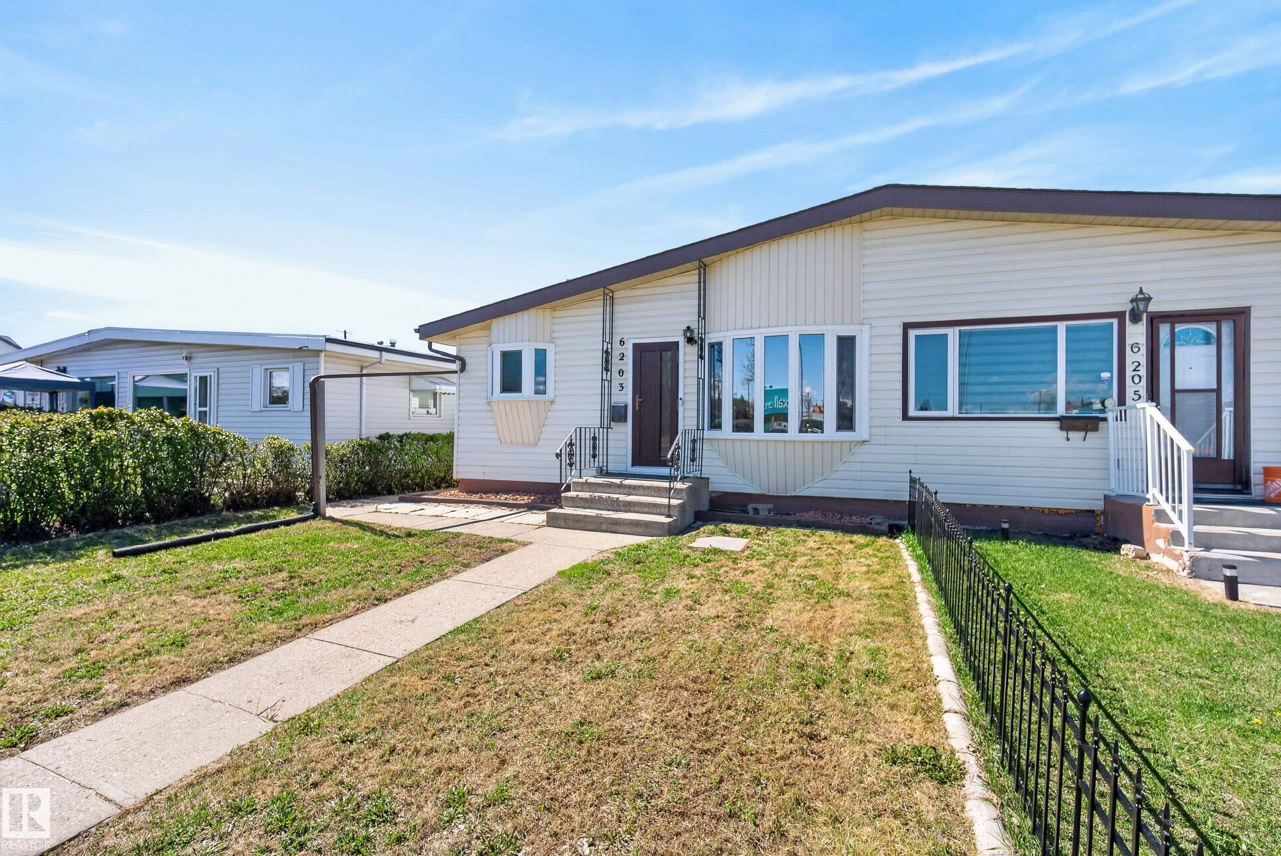 Cream-colored siding exterior featuring a multi-pane bay window and brown trim - 6203 90 Avenue, Edmonton, AB
