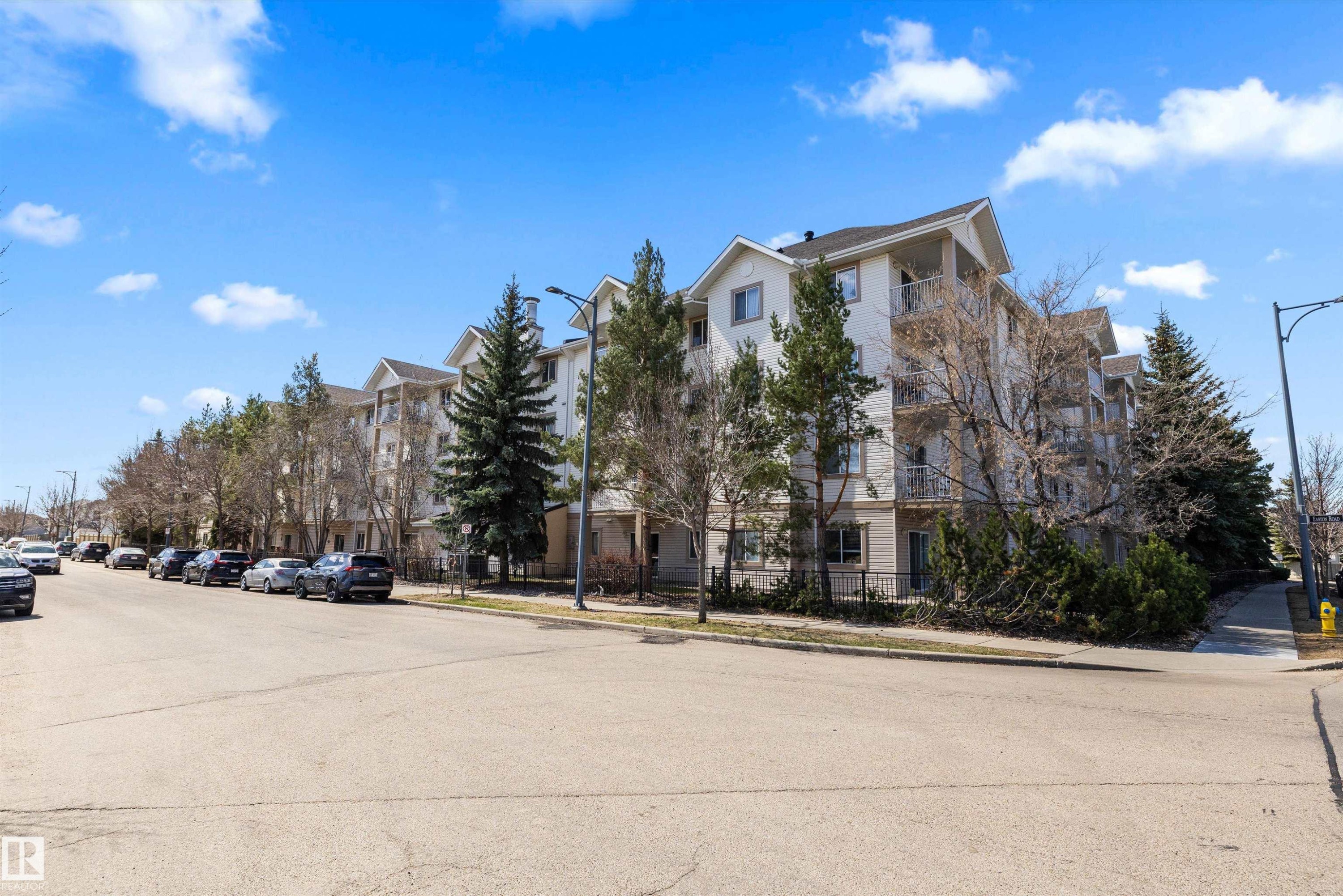 Multi-story residential building featuring light-toned siding and gabled rooflines - 320 245 Edwards Drive, Edmonton, AB