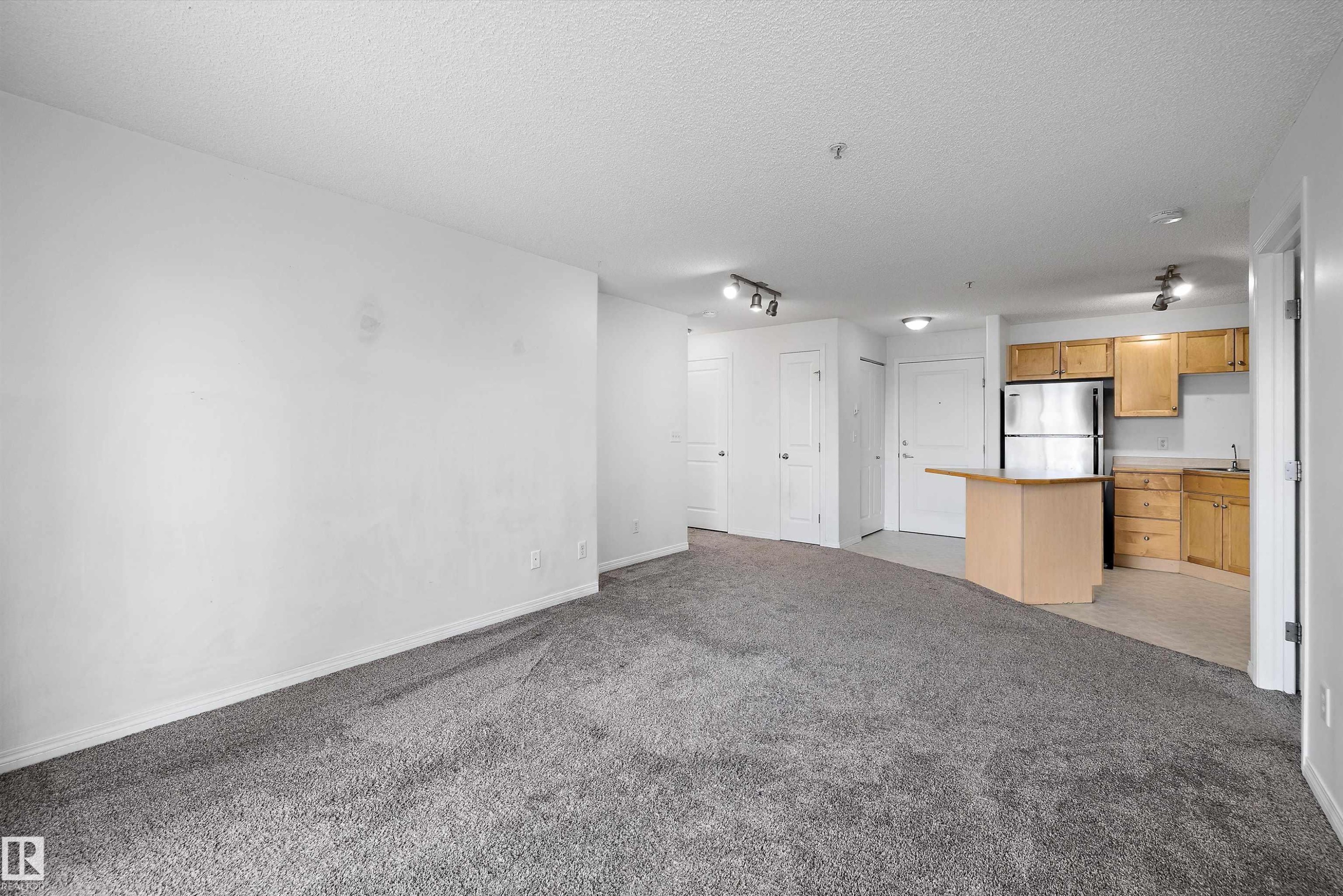 Open-concept living space featuring neutral grey carpeting and white walls - 320 245 Edwards Drive, Edmonton, AB