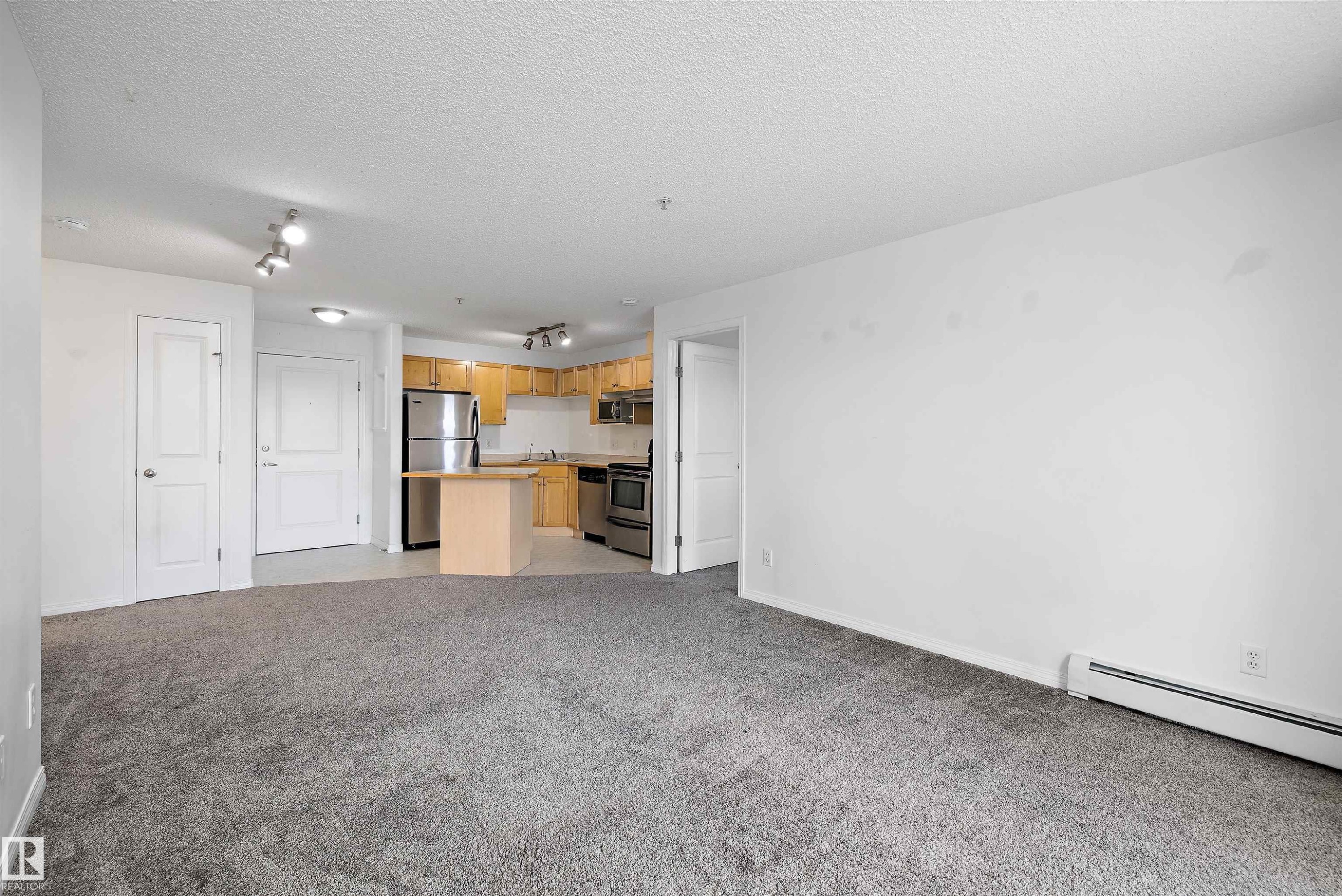 Open-concept living space featuring gray carpet flooring and white walls - 320 245 Edwards Drive, Edmonton, AB