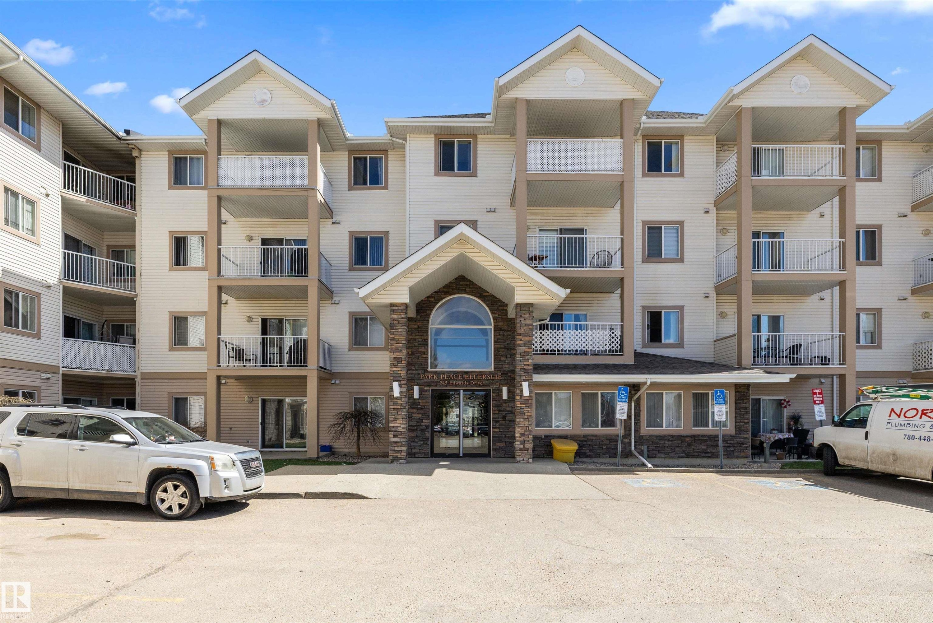 Multi-story building featuring a stone and siding facade, multiple private balconies, and a central arched entrance - 320 245 Edwards Drive, Edmonton, AB