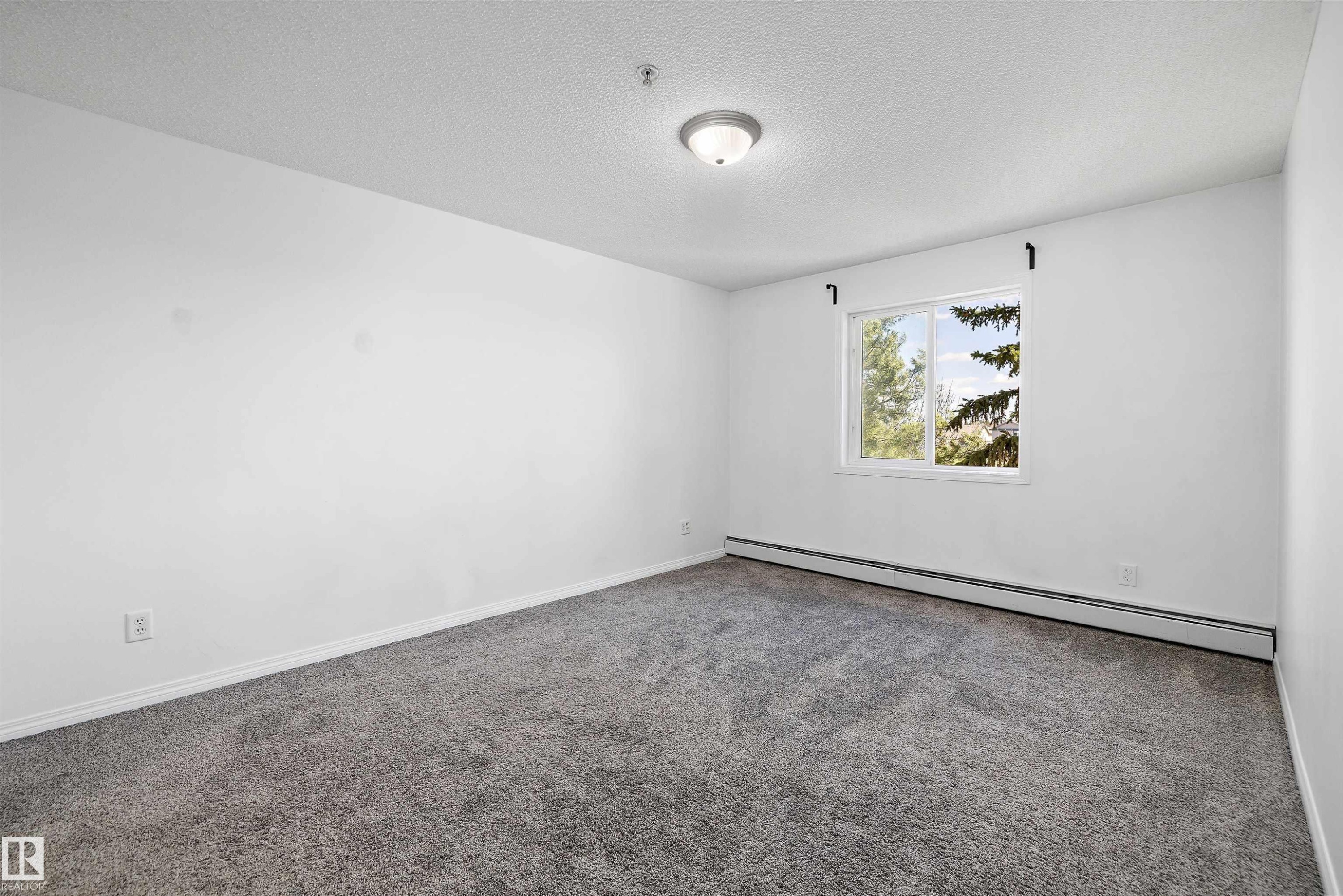 Carpeted room with white walls, a single window, and a flush-mount ceiling light fixture - 320 245 Edwards Drive, Edmonton, AB