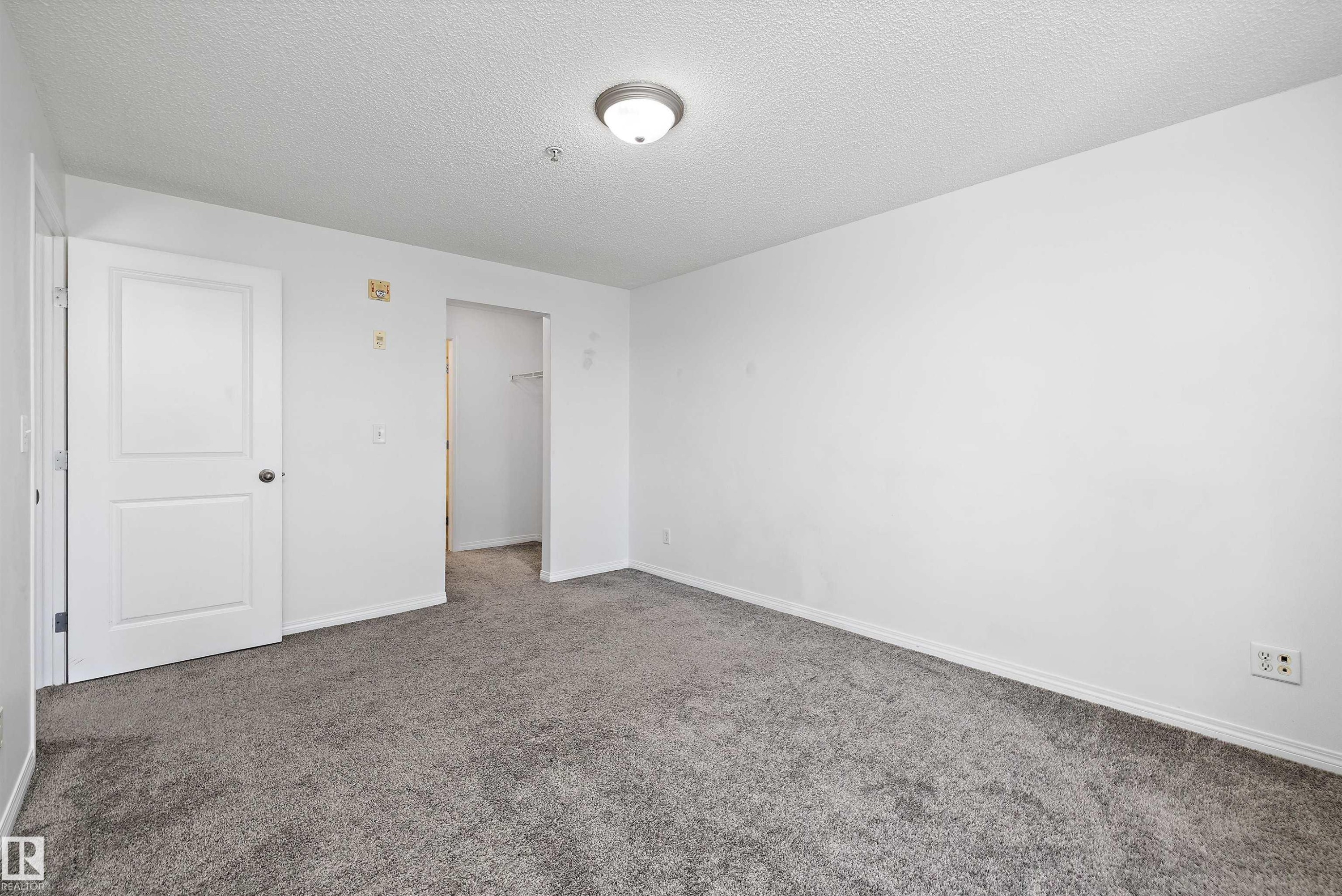 Neutral-toned carpet flooring complementing white walls and trim - 320 245 Edwards Drive, Edmonton, AB