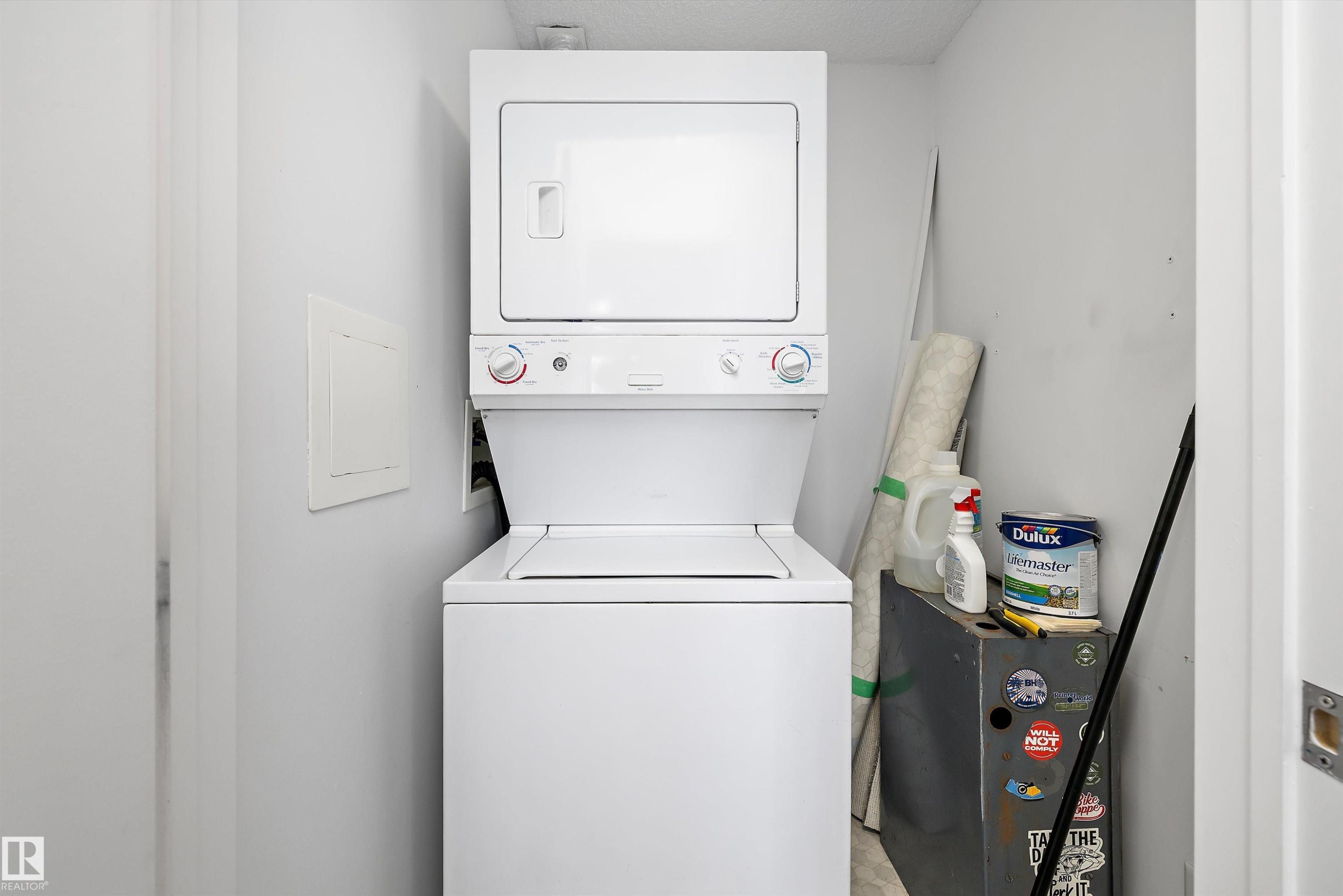 Dedicated laundry area with a white stackable washer and dryer unit - 320 245 Edwards Drive, Edmonton, AB