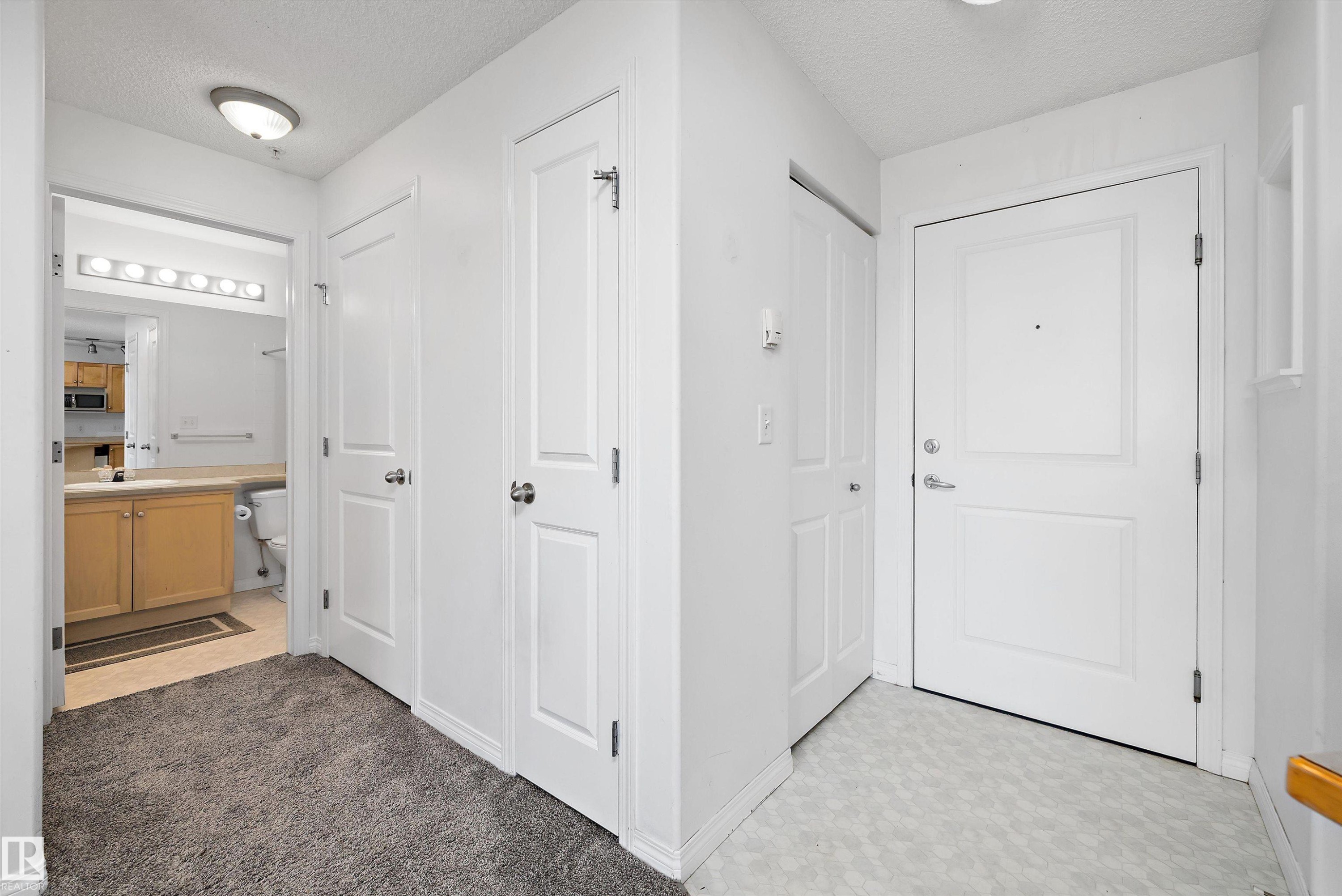 Foyer featuring a white paneled entry door, a neutral tile-look floor, and a flush mount ceiling light - 320 245 Edwards Drive, Edmonton, AB