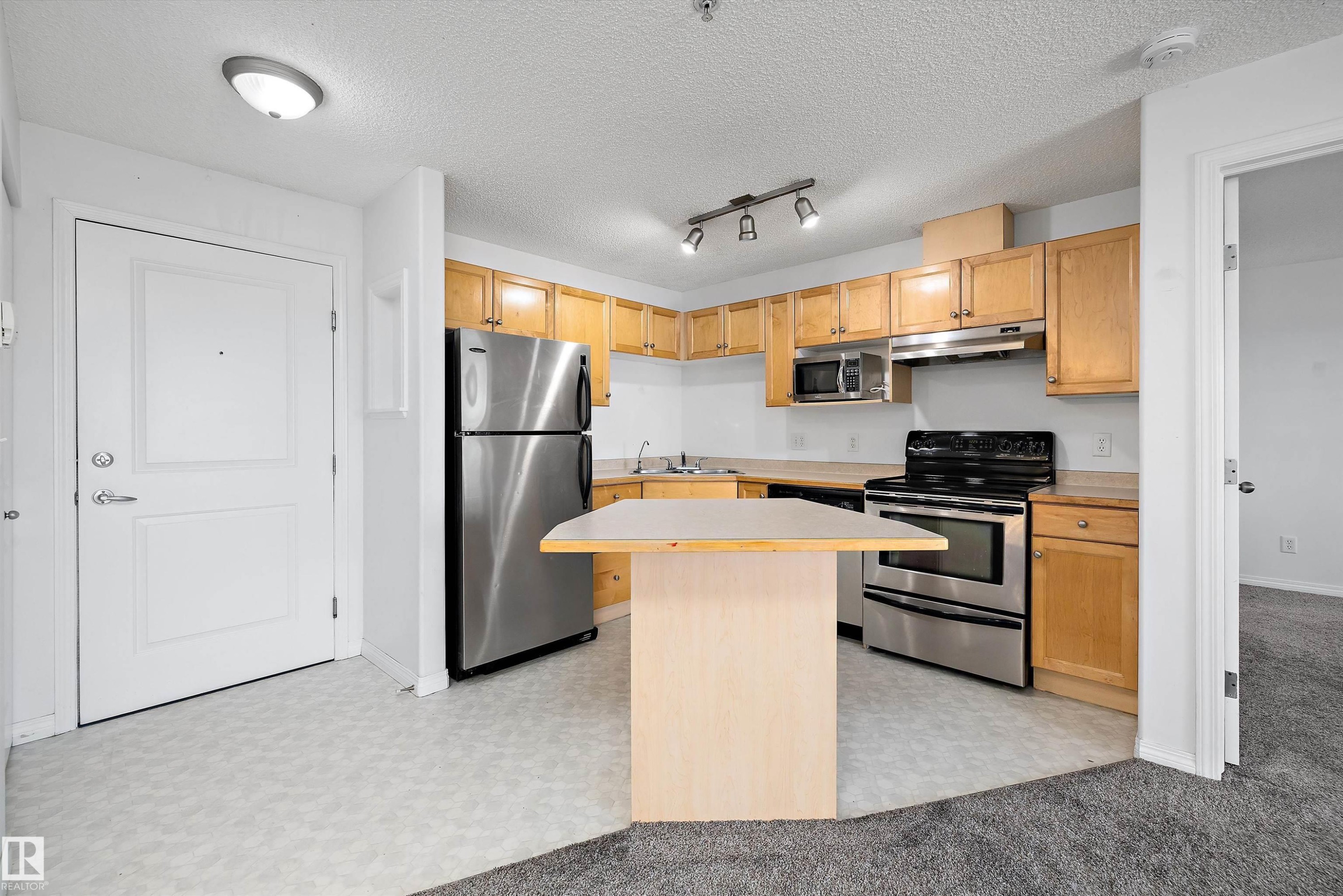 Kitchen featuring light wood cabinetry and stainless steel appliances - 320 245 Edwards Drive, Edmonton, AB