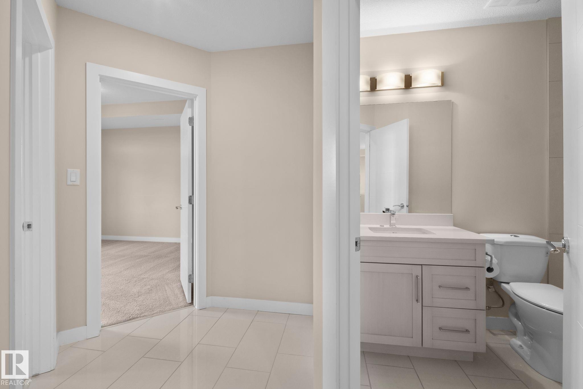 Hallway featuring light-toned tile flooring, neutral wall paint, white baseboards, and white door casings - 309 625 Leger Way, Edmonton, AB