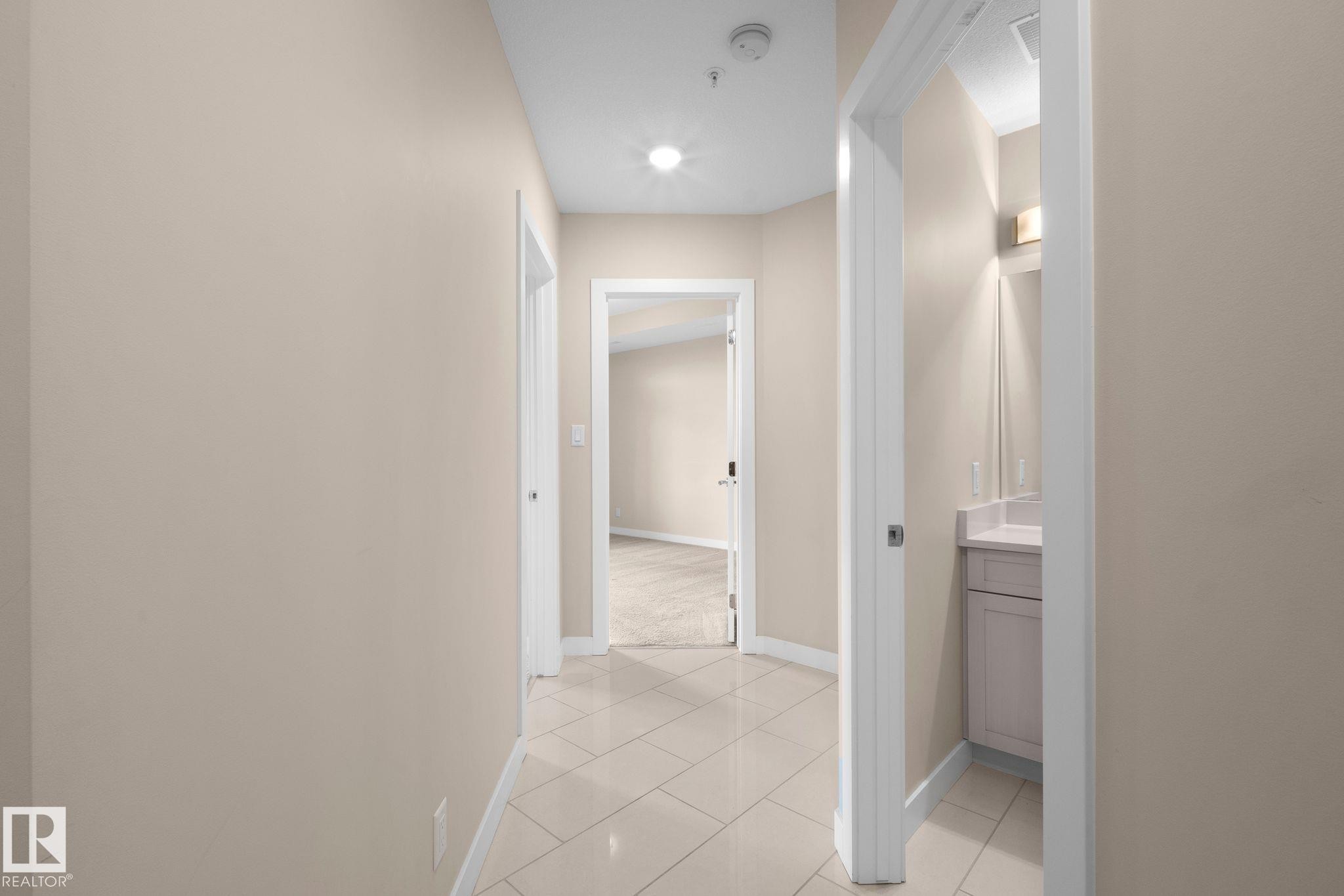Hallway featuring neutral-toned walls, tile flooring, and recessed lighting - 309 625 Leger Way, Edmonton, AB