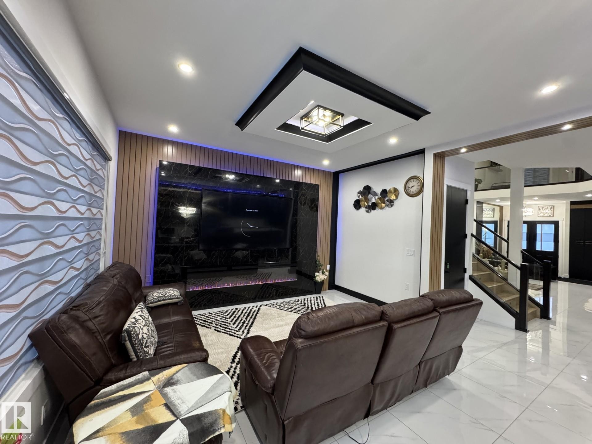 Living area featuring a ceiling inset with recessed lighting, a built-in media wall with dark stone-finish paneling, and wood-finish accent wall panels - 2123 18 Avenue, Edmonton, AB