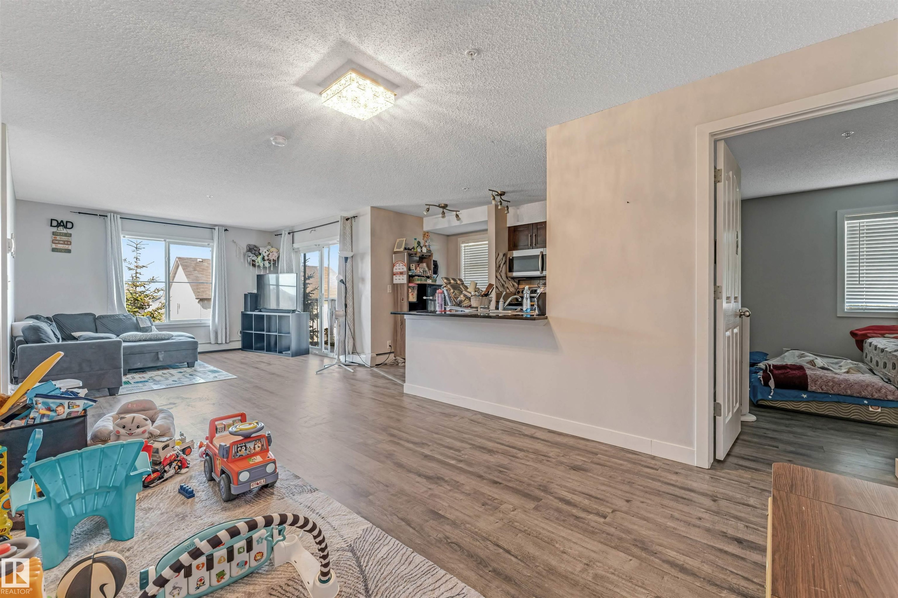 Open-concept living space with wood-finish flooring extending throughout - 320 534 Watt Boulevard, Edmonton, AB - Indoor Photo Showing Living Room