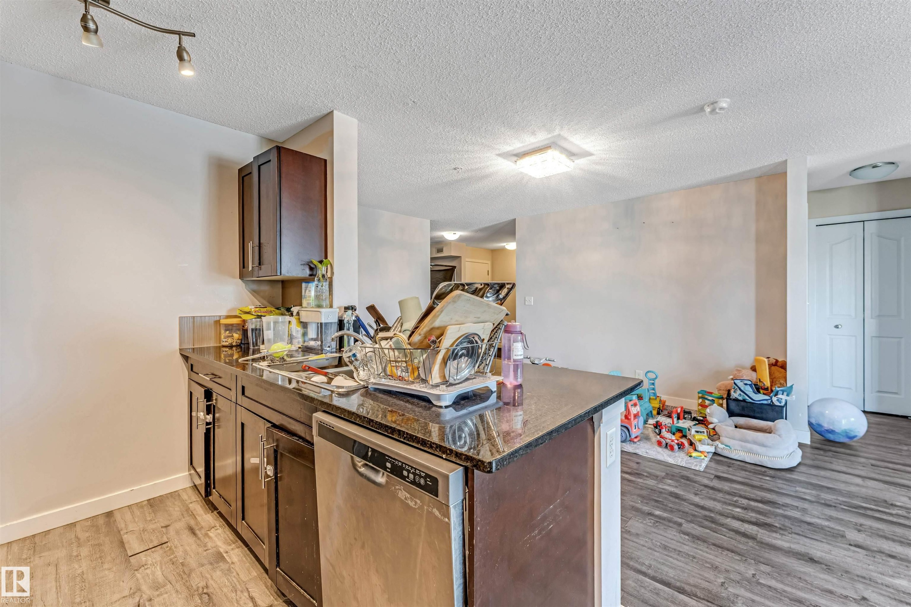 Kitchen island with dark cabinetry and a polished stone countertop - 320 534 Watt Boulevard, Edmonton, AB - Indoor Photo Showing Kitchen With Double Sink