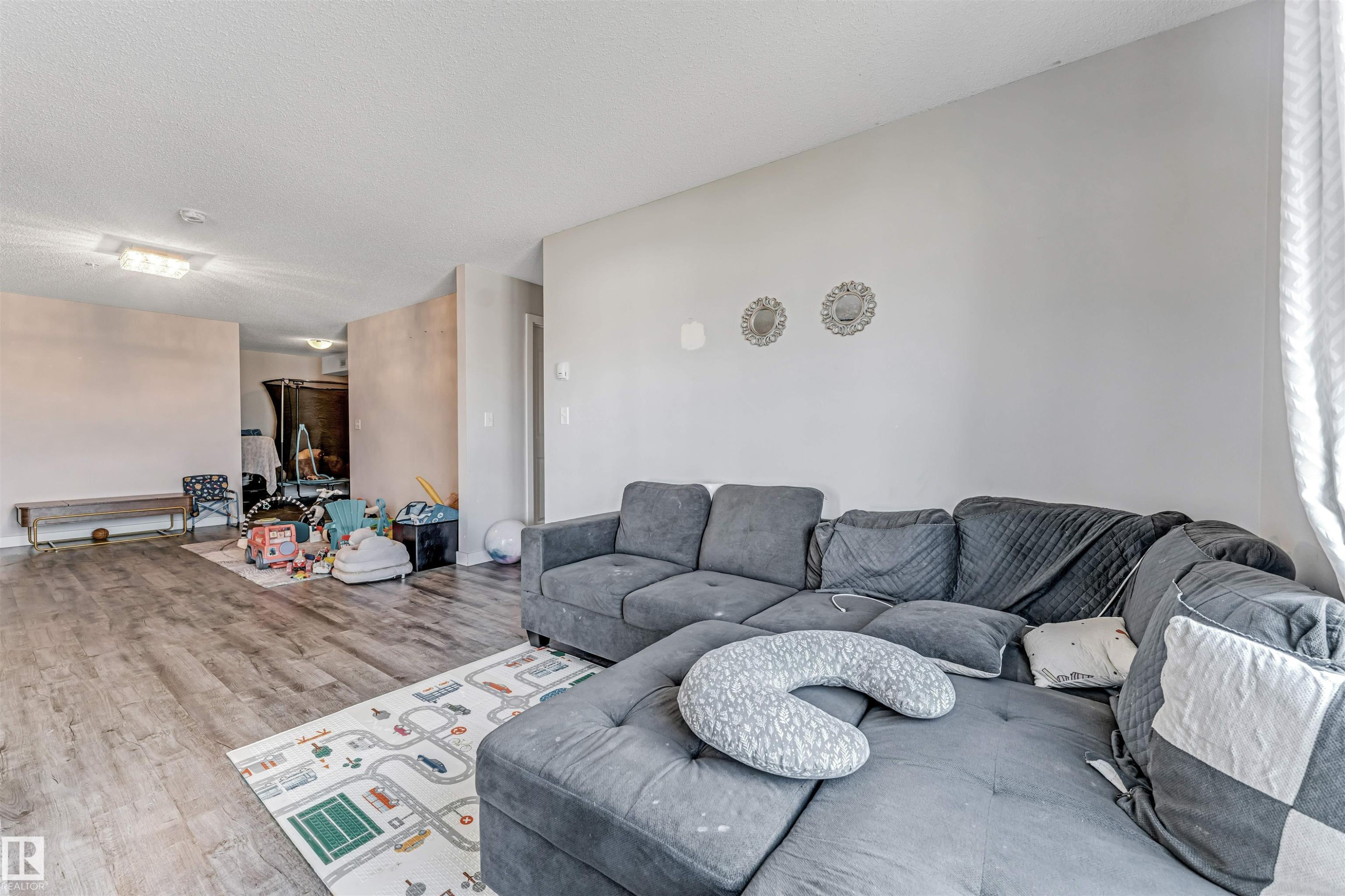Open-concept interior featuring wood-finish flooring, light neutral wall paint, and recessed lighting - 320 534 Watt Boulevard, Edmonton, AB - Indoor Photo Showing Living Room