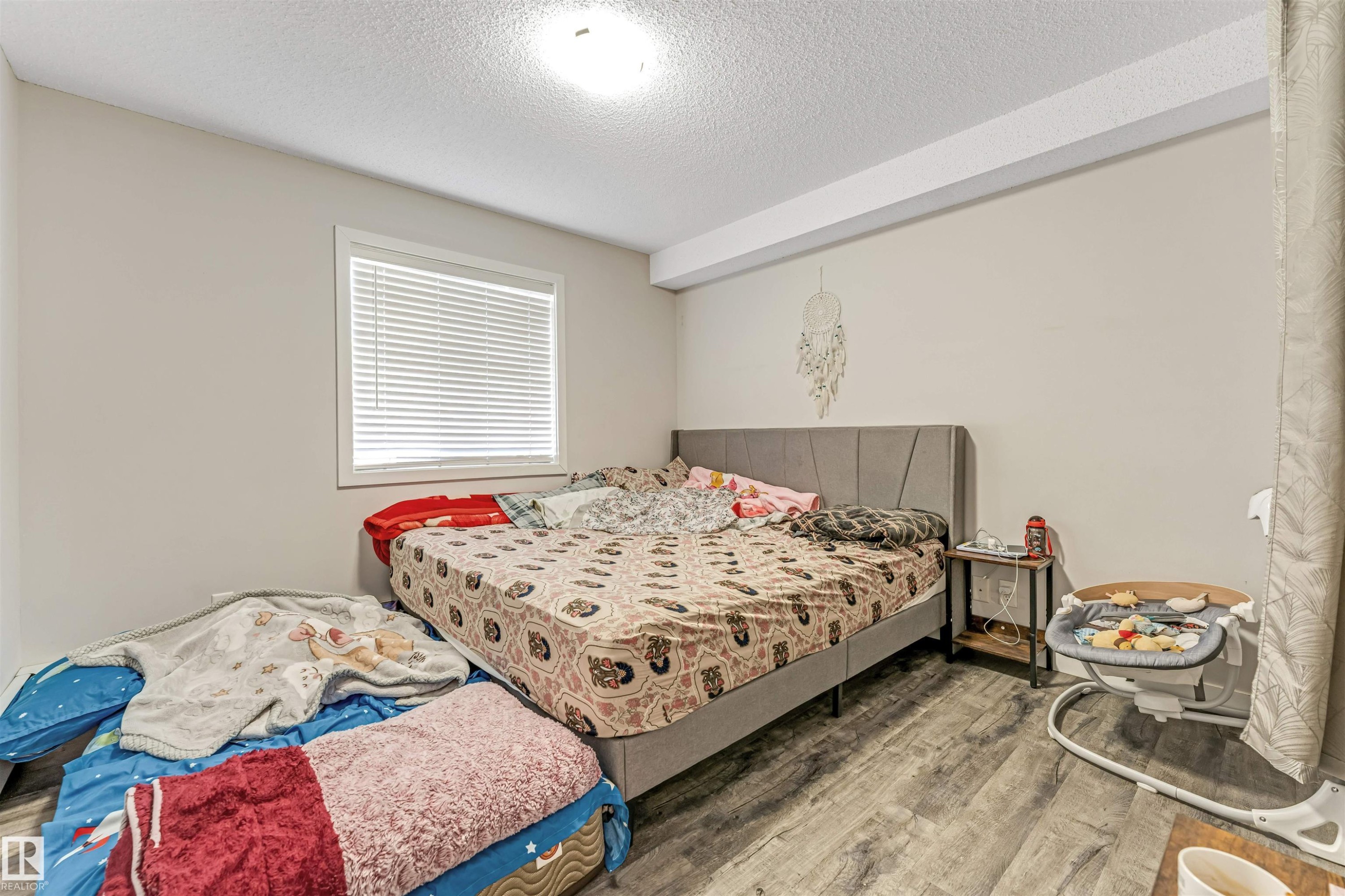 Room featuring wood-finish flooring, a single window with blinds, and light-toned wall paint - 320 534 Watt Boulevard, Edmonton, AB - Indoor Photo Showing Bedroom