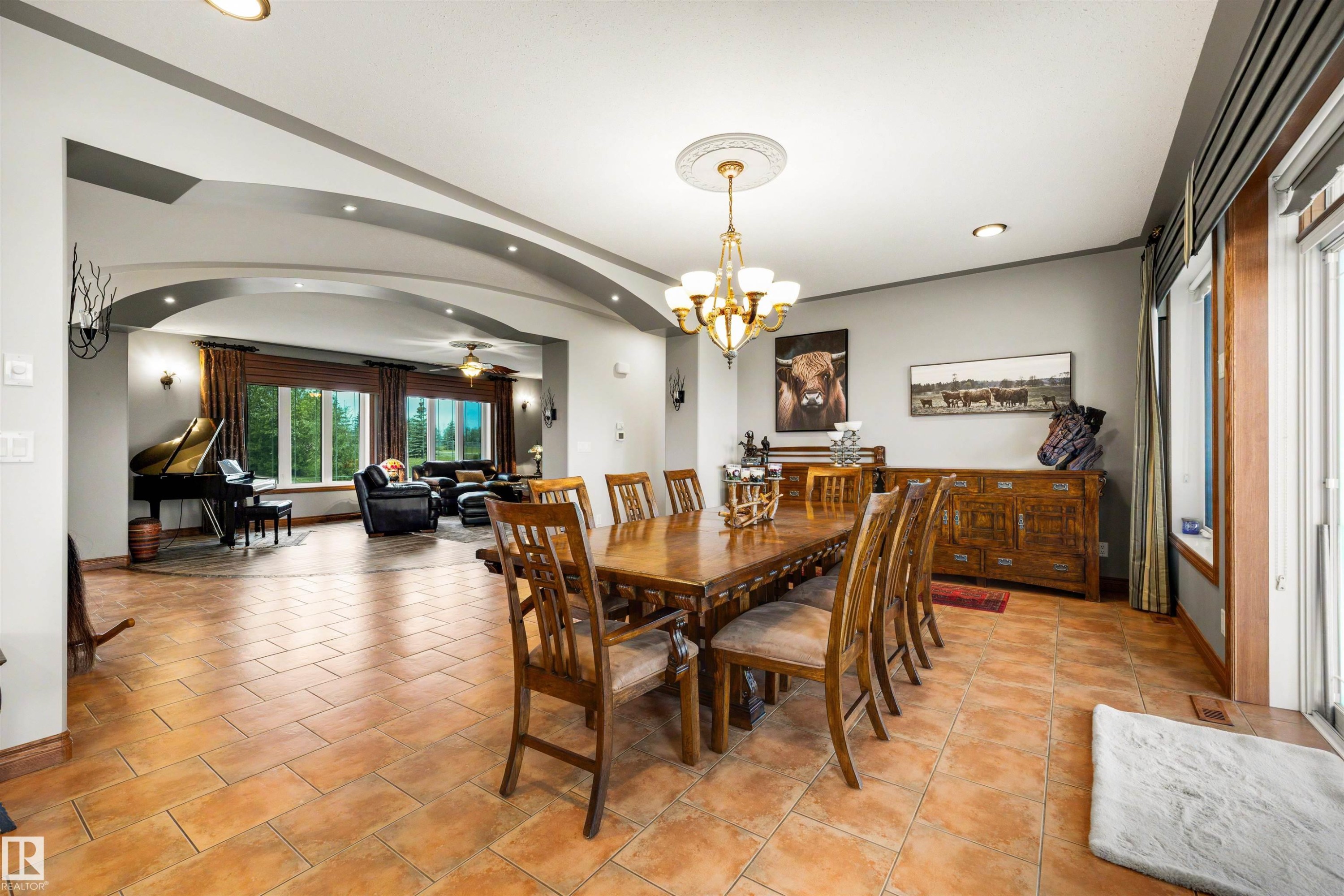 Spacious dining area featuring terra cotta tile flooring, an ornate chandelier with ceiling medallion, and a large window with exterior access - 28125 Highway 587, Rural Red Deer County, AB - Indoor Photo Showing Dining Room