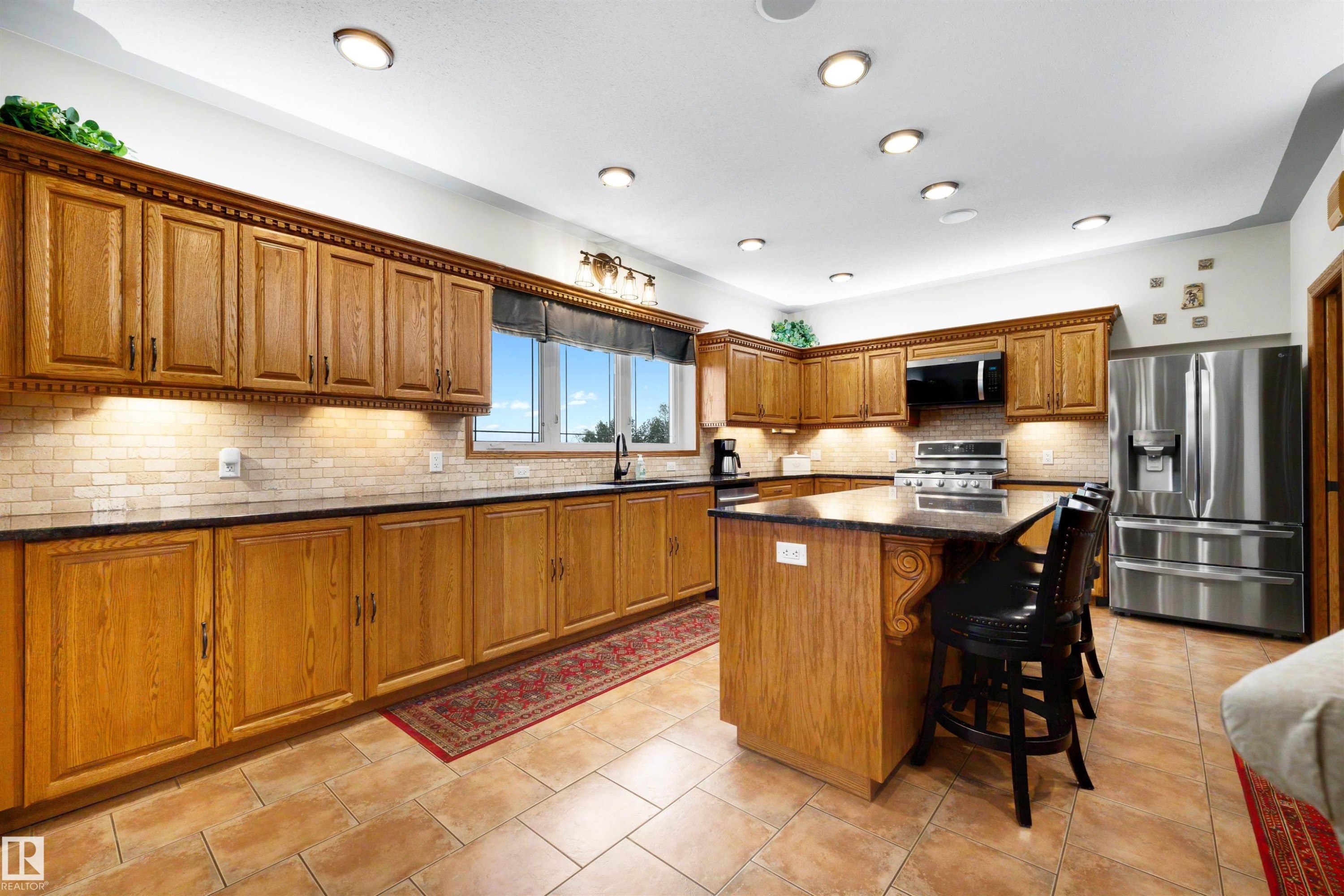 Kitchen featuring extensive wood cabinetry, dark countertops, a tile backsplash, and recessed lighting - 28125 Highway 587, Rural Red Deer County, AB - Indoor Photo Showing Kitchen