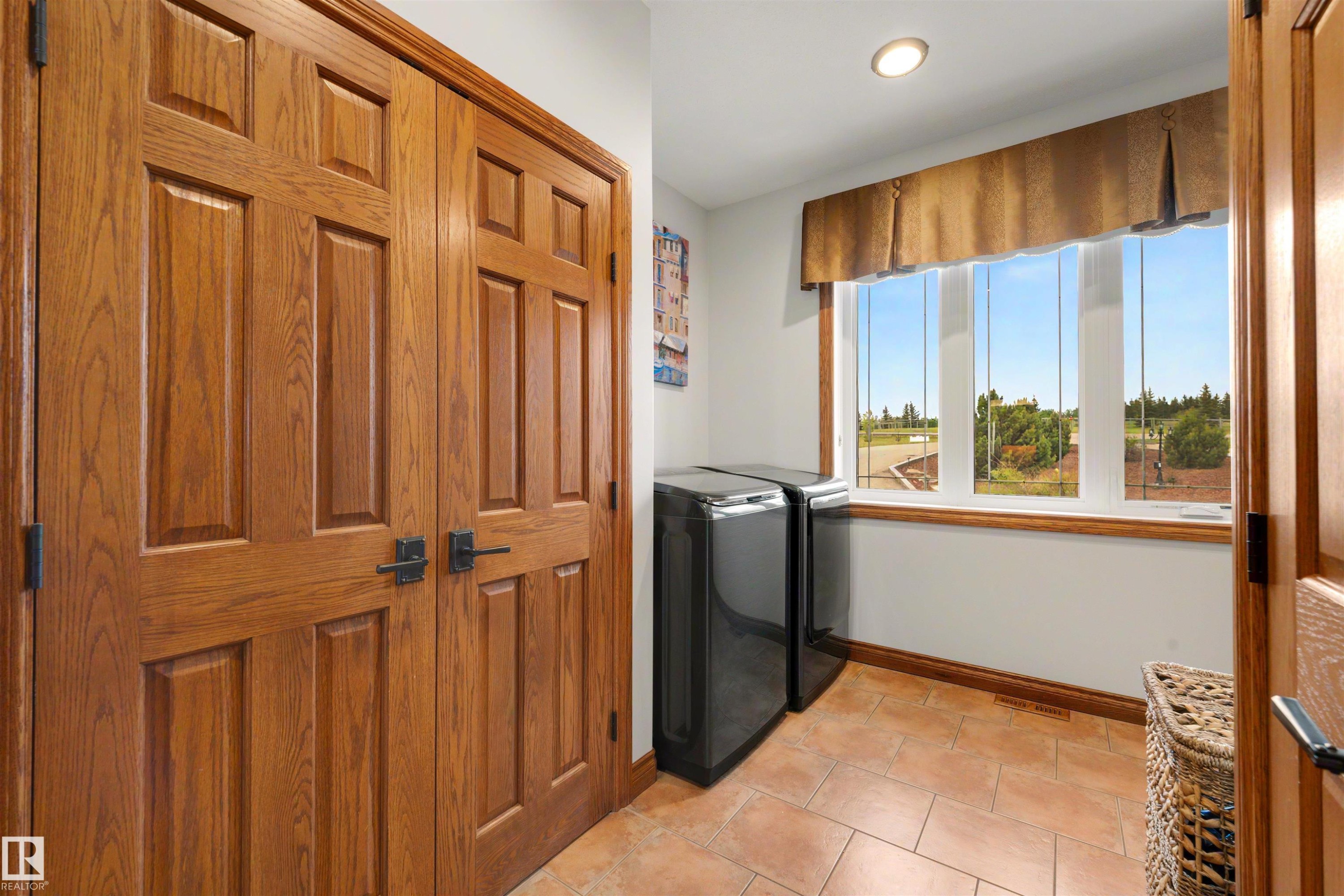 Laundry area featuring a large window with wood trim, recessed lighting, tile flooring, and paneled wood doors - 28125 Highway 587, Rural Red Deer County, AB - Indoor