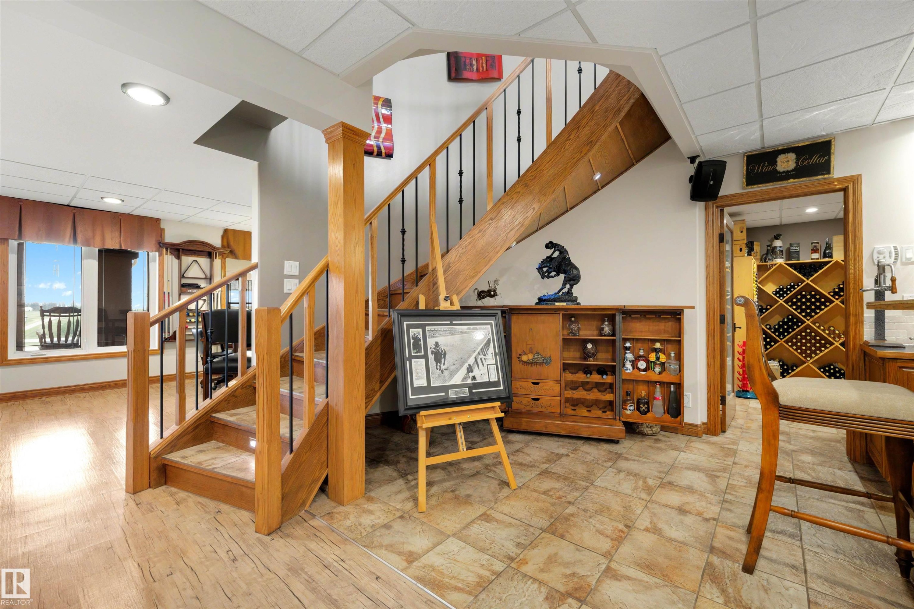 Wood-finish flooring and tile flooring define distinct areas, complemented by a wooden staircase with black iron spindles - 28125 Highway 587, Rural Red Deer County, AB - Indoor Photo Showing Other Room