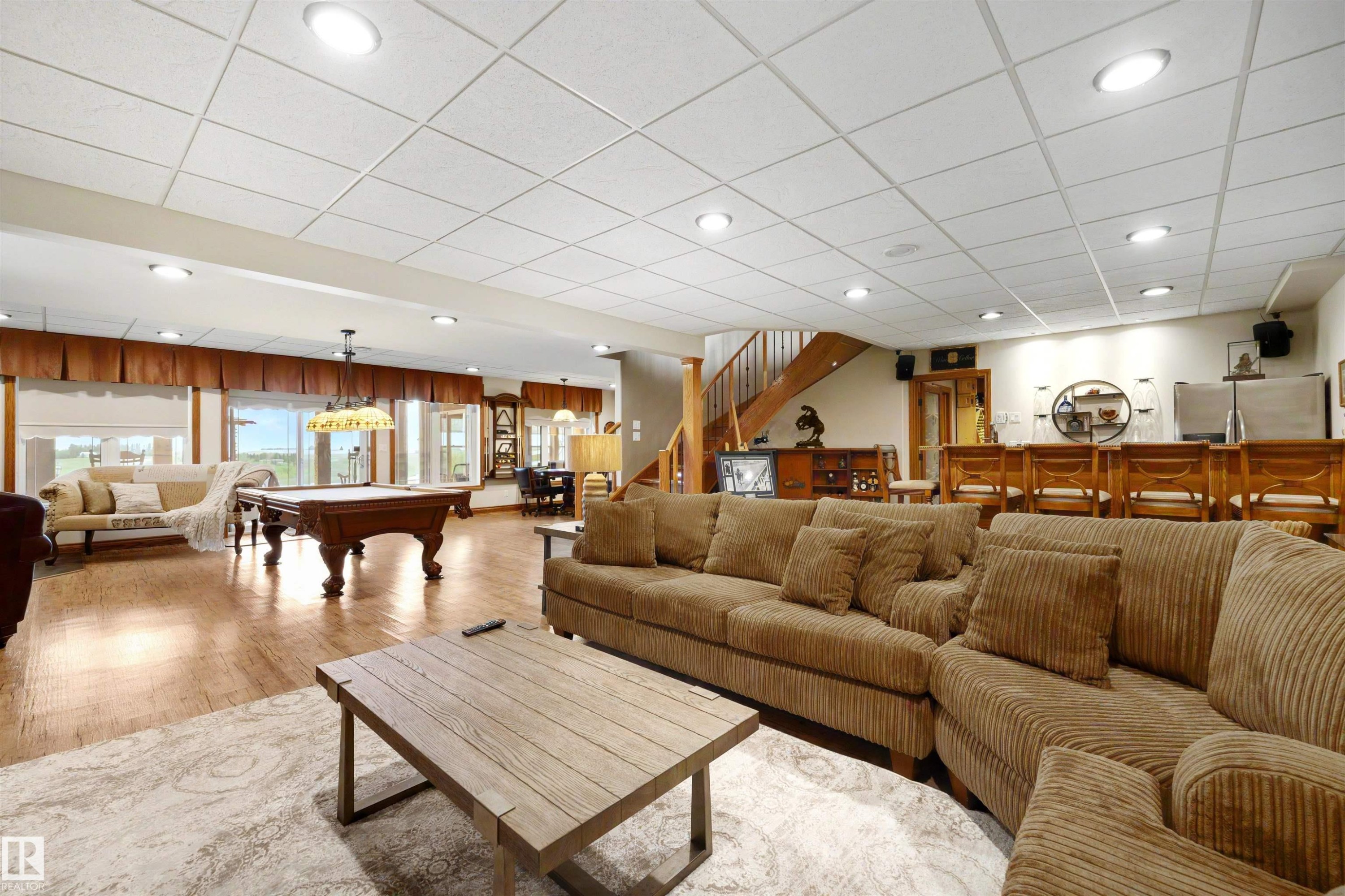 Spacious lower level featuring wood-finish flooring, recessed lighting, and a built-in bar area with seating - 28125 Highway 587, Rural Red Deer County, AB - Indoor