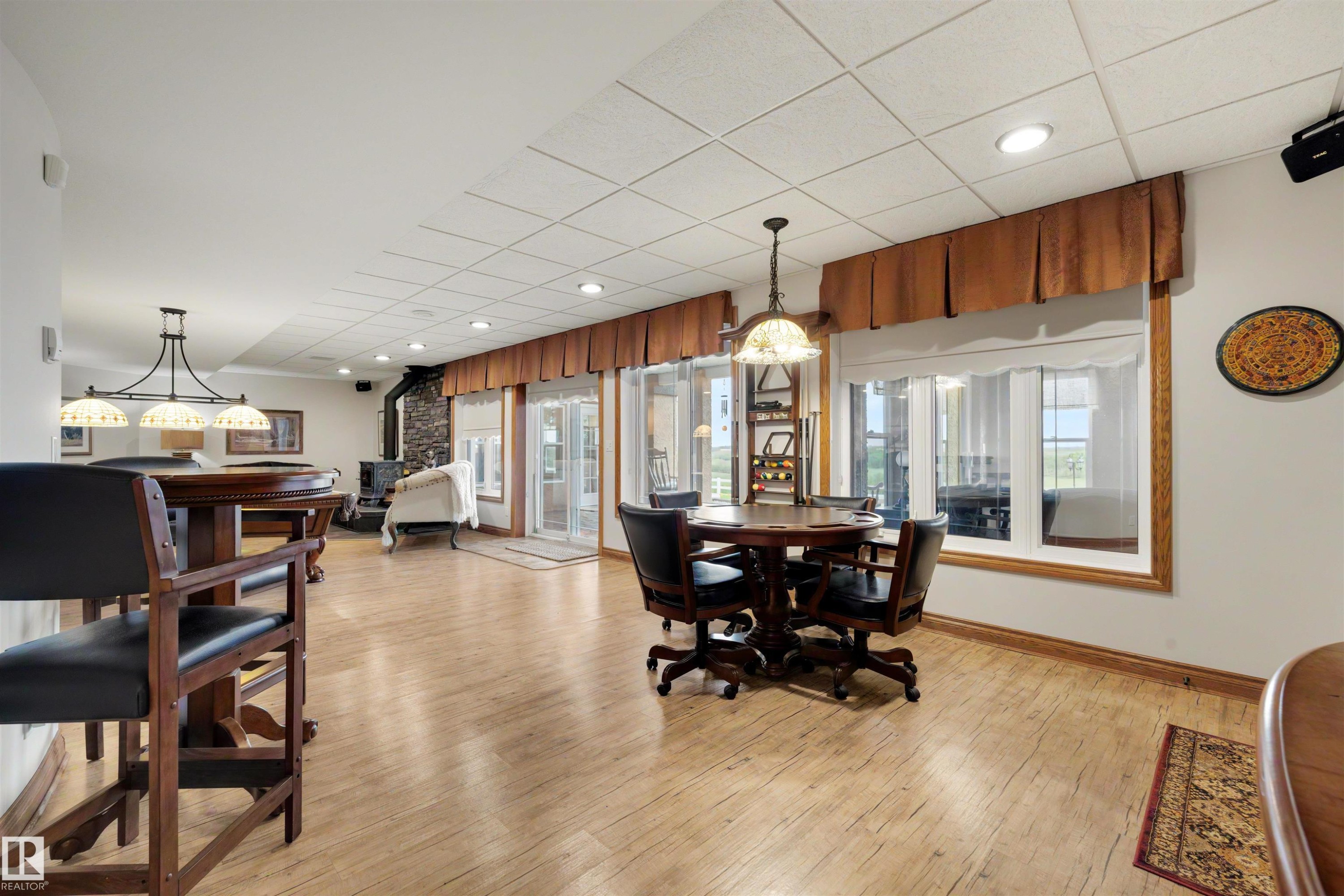 Spacious recreation area featuring light wood-finish flooring, recessed lighting, and multiple large windows - 28125 Highway 587, Rural Red Deer County, AB - Indoor