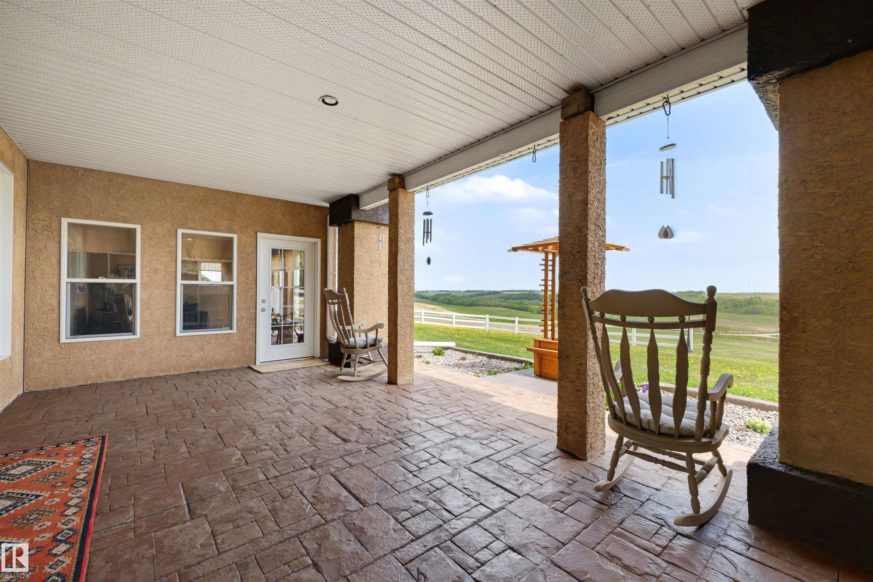 Expansive covered patio featuring stamped concrete flooring, stucco exterior walls, and a white paneled ceiling with recessed lighting - 28125 Highway 587, Rural Red Deer County, AB - Outdoor With Deck Patio Veranda With Exterior