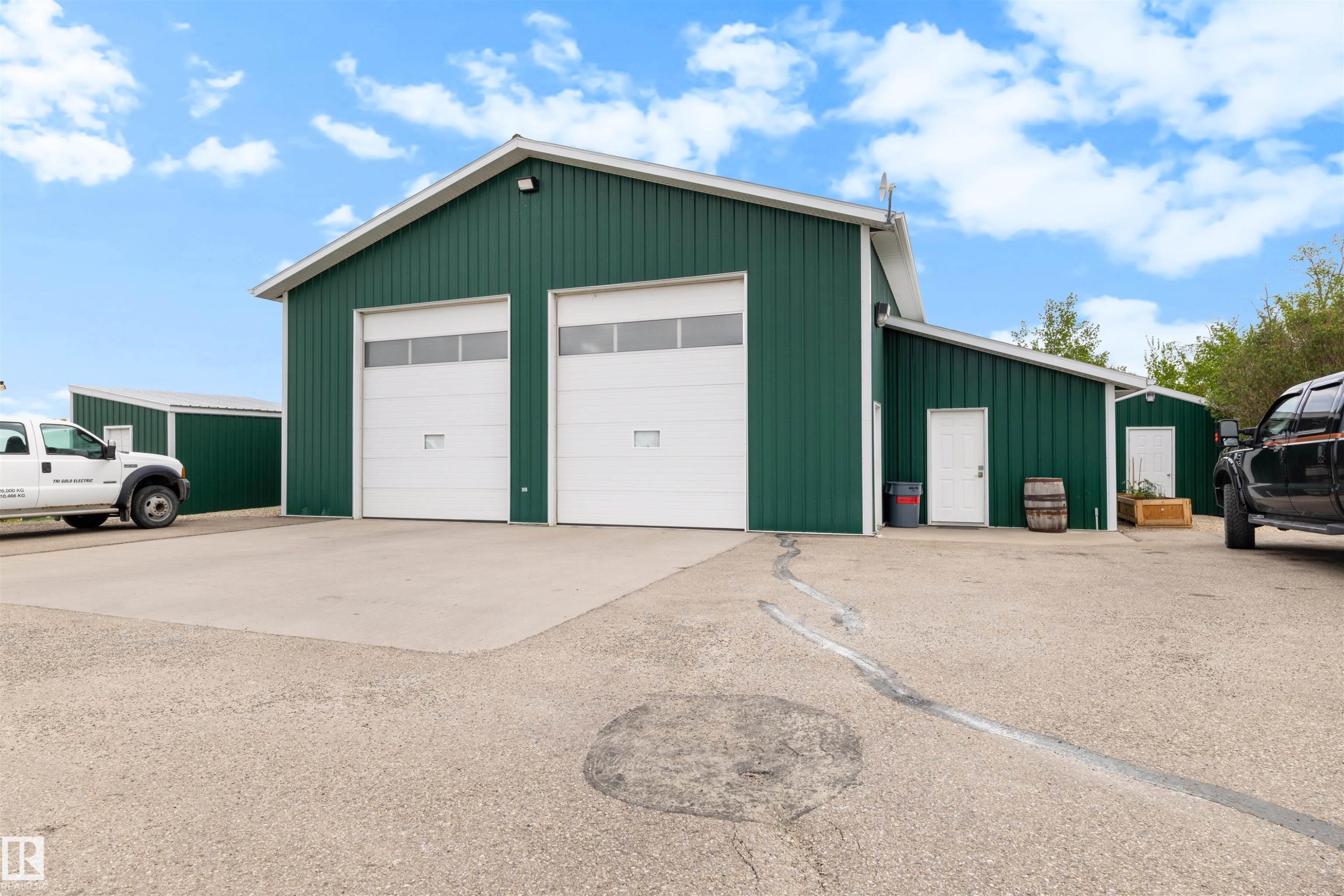 Metal-sided building with two large white overhead doors, an additional entry door, and a concrete apron - 28125 Highway 587, Rural Red Deer County, AB - Outdoor With Exterior