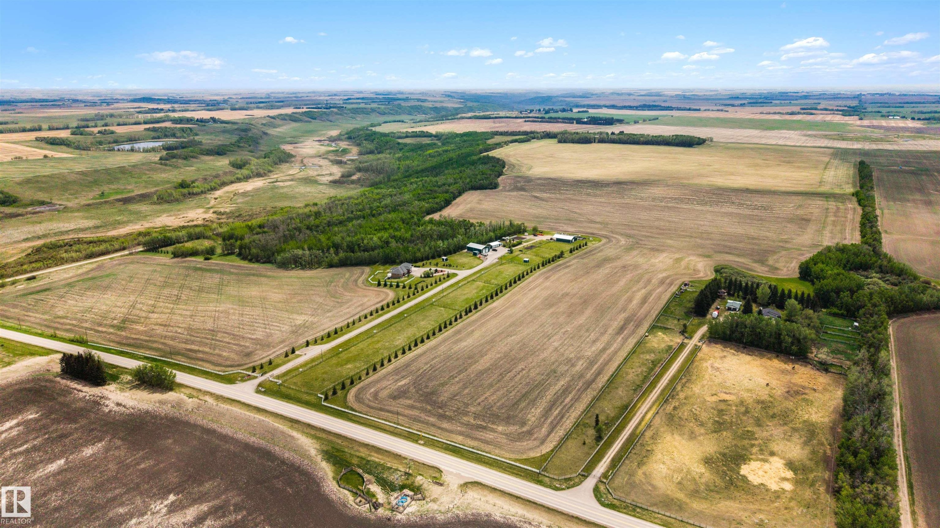 Expansive agricultural land featuring cultivated fields, natural tree lines, and a distant water feature - 28125 Highway 587, Rural Red Deer County, AB - Outdoor With View