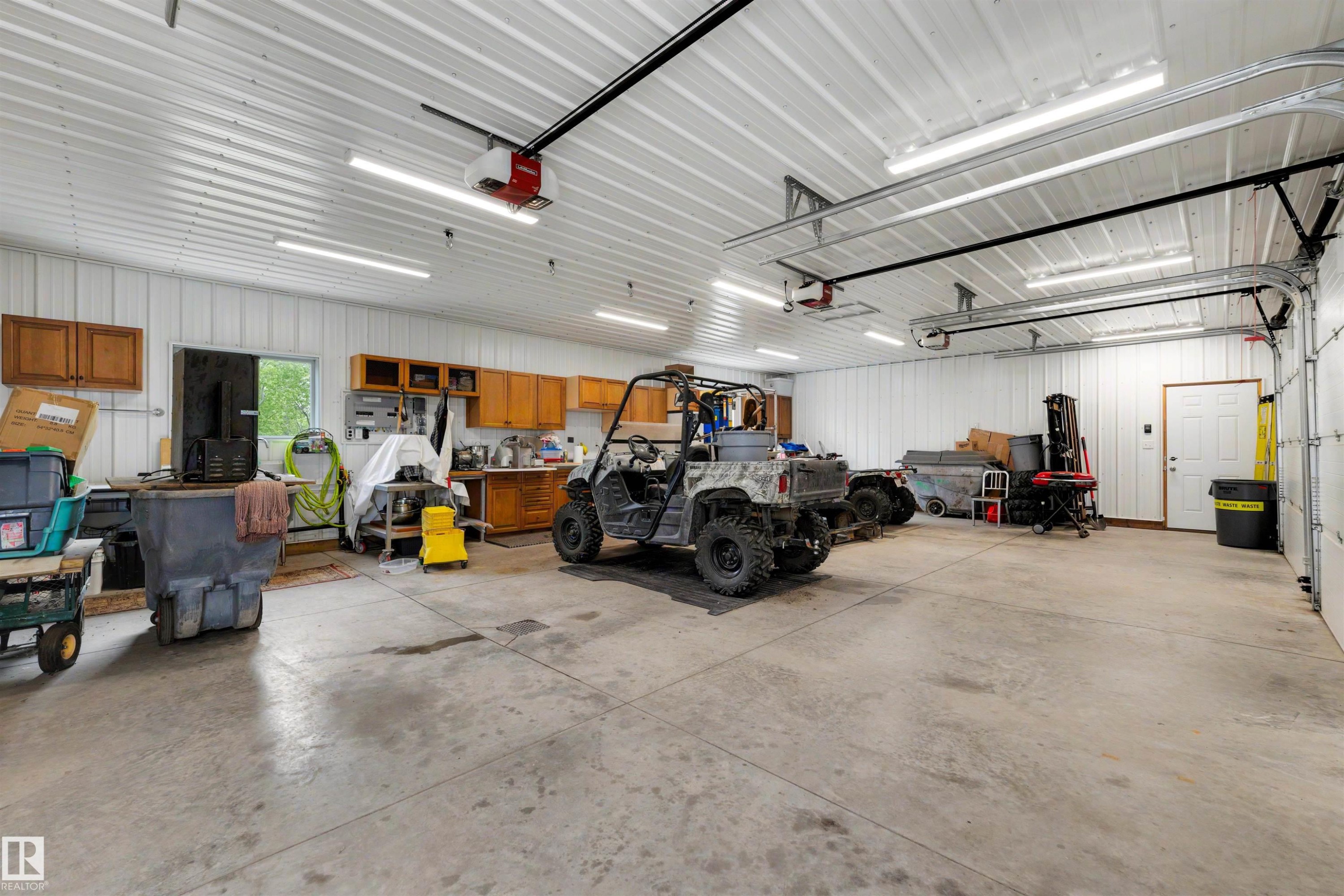 Spacious garage with multiple overhead doors, concrete flooring, and extensive overhead lighting - 28125 Highway 587, Rural Red Deer County, AB - Indoor Photo Showing Garage
