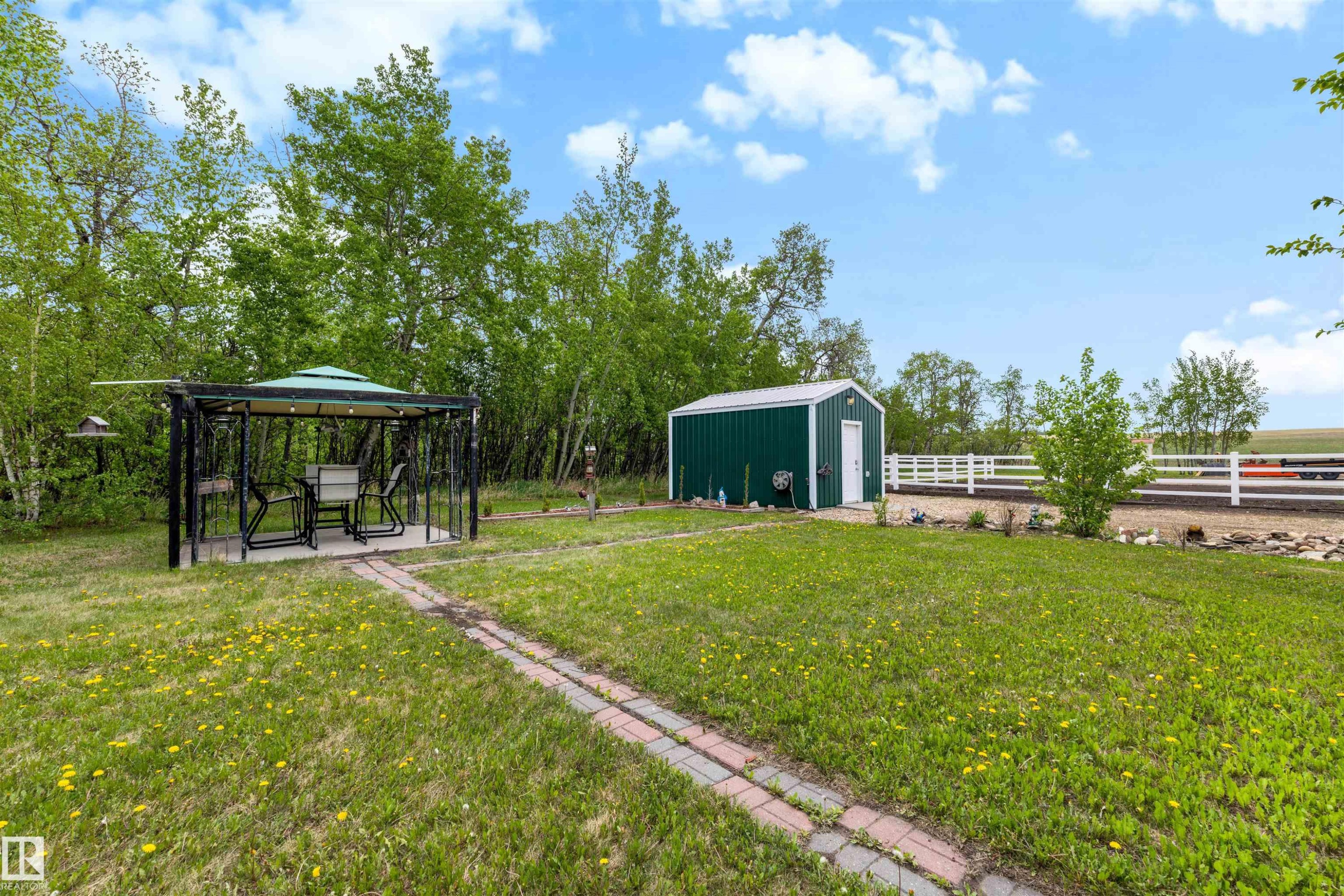 Expansive green lawn featuring a paved walkway, a gazebo with a concrete pad, and a detached storage shed - 28125 Highway 587, Rural Red Deer County, AB - Outdoor