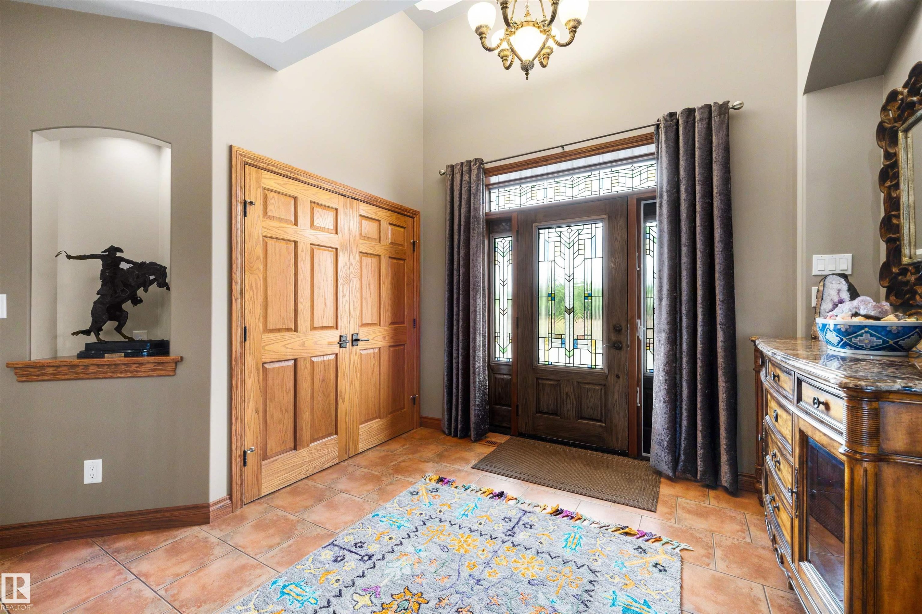 Entryway featuring a wood-paneled front door with decorative glass inserts and sidelights, a transom window, and a chandelier light fixture - 28125 Highway 587, Rural Red Deer County, AB - Indoor Photo Showing Other Room