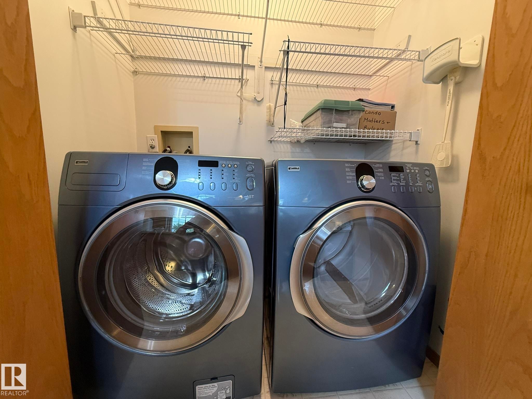 Dedicated laundry space featuring a side-by-side washer and dryer, front-loading design, and wall-mounted wire shelving - 102 4610 50 Avenue, Stony Plain, AB