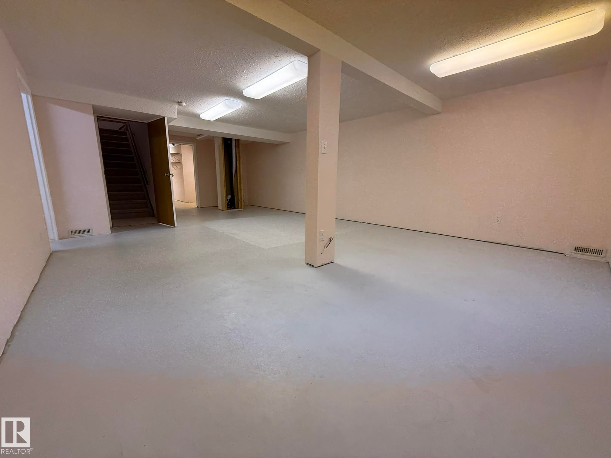Spacious lower level featuring light-colored flooring, recessed lighting fixtures, and exposed ceiling beams - 102 4610 50 Avenue, Stony Plain, AB