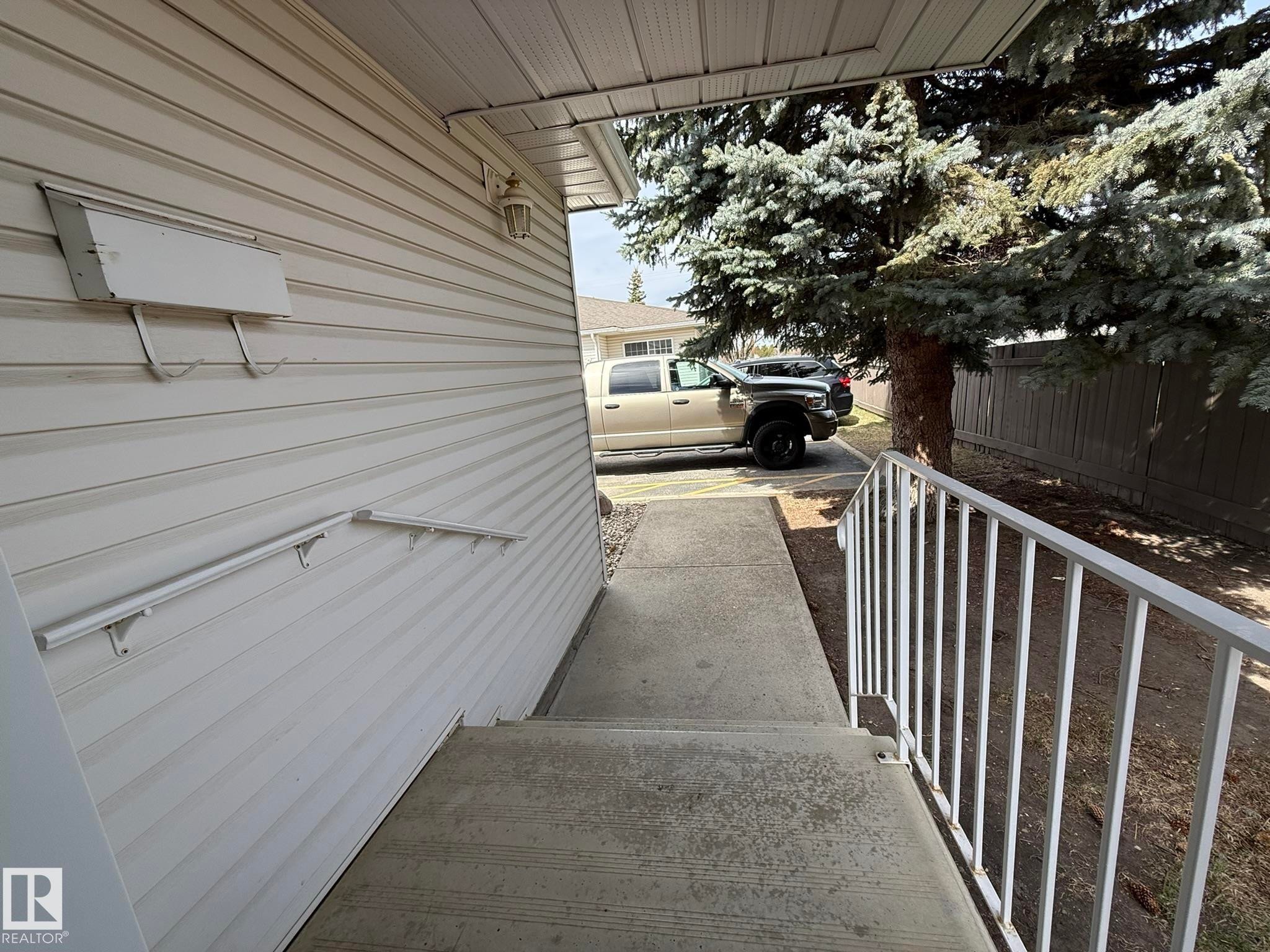 Exterior entrance with concrete steps and an aluminum handrail - 102 4610 50 Avenue, Stony Plain, AB