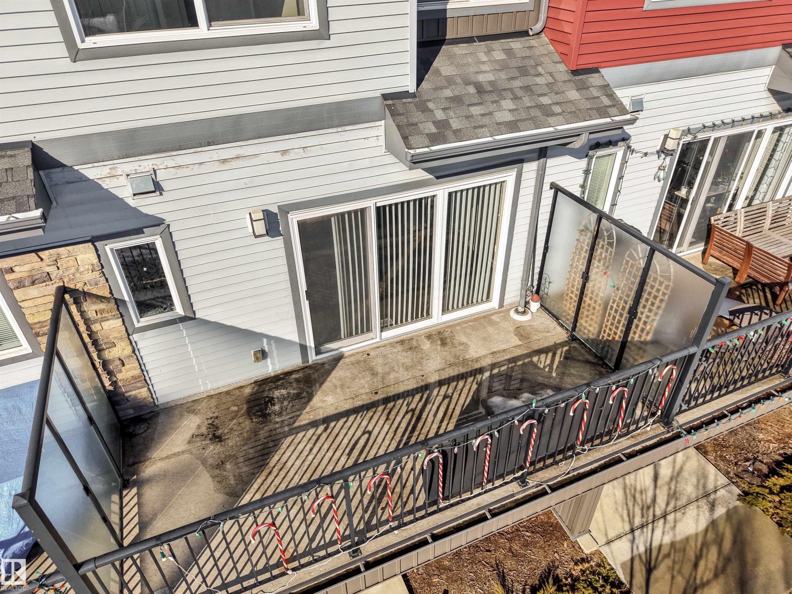 Outdoor patio area featuring a concrete surface, black metal railing with glass panels, and sliding glass door access - 1624 33A Street, Edmonton, AB