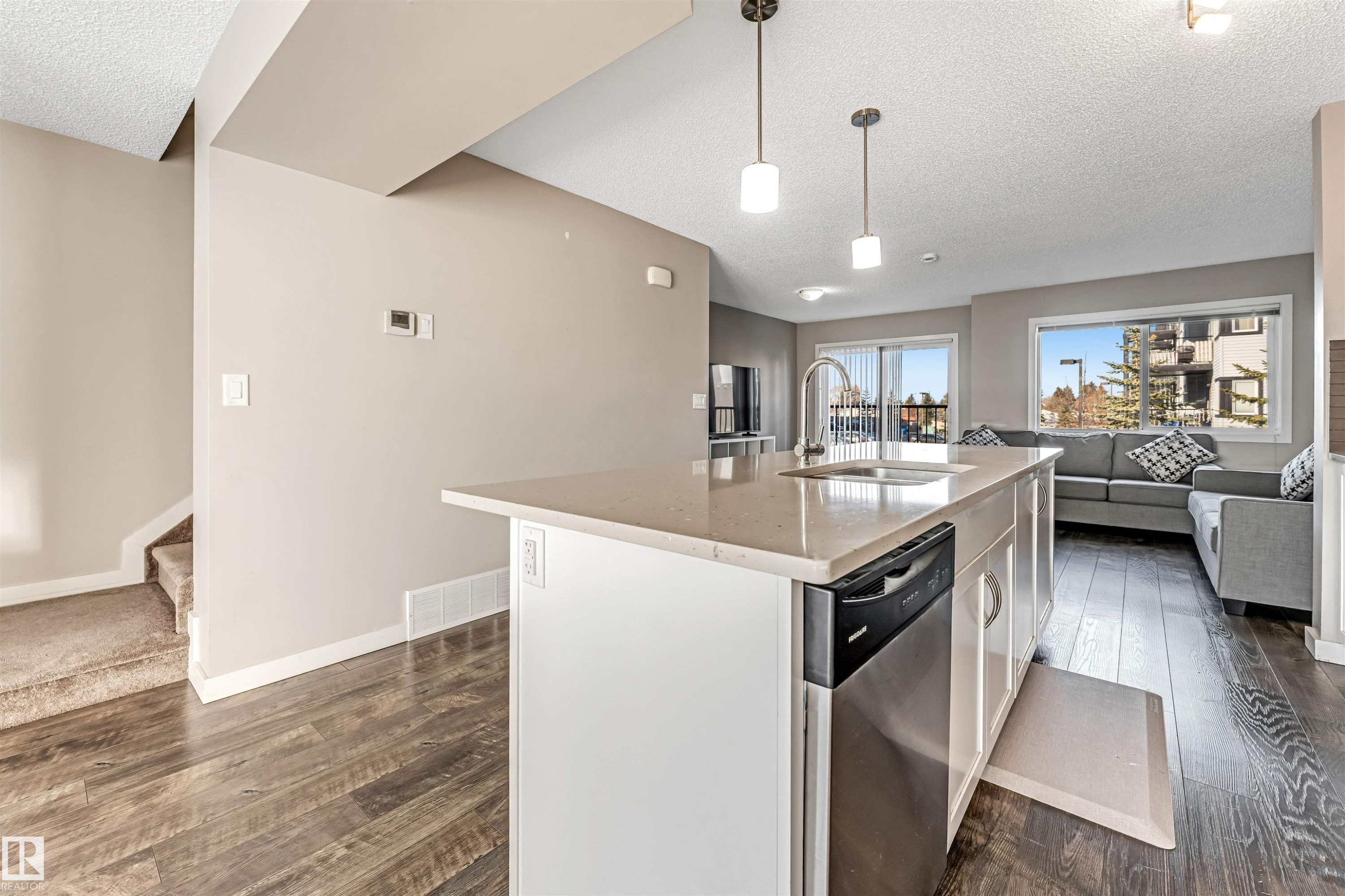 Kitchen island featuring a stainless steel dishwasher, an undermount sink with a high-arc faucet, and pendant lighting - 1624 33A Street, Edmonton, AB