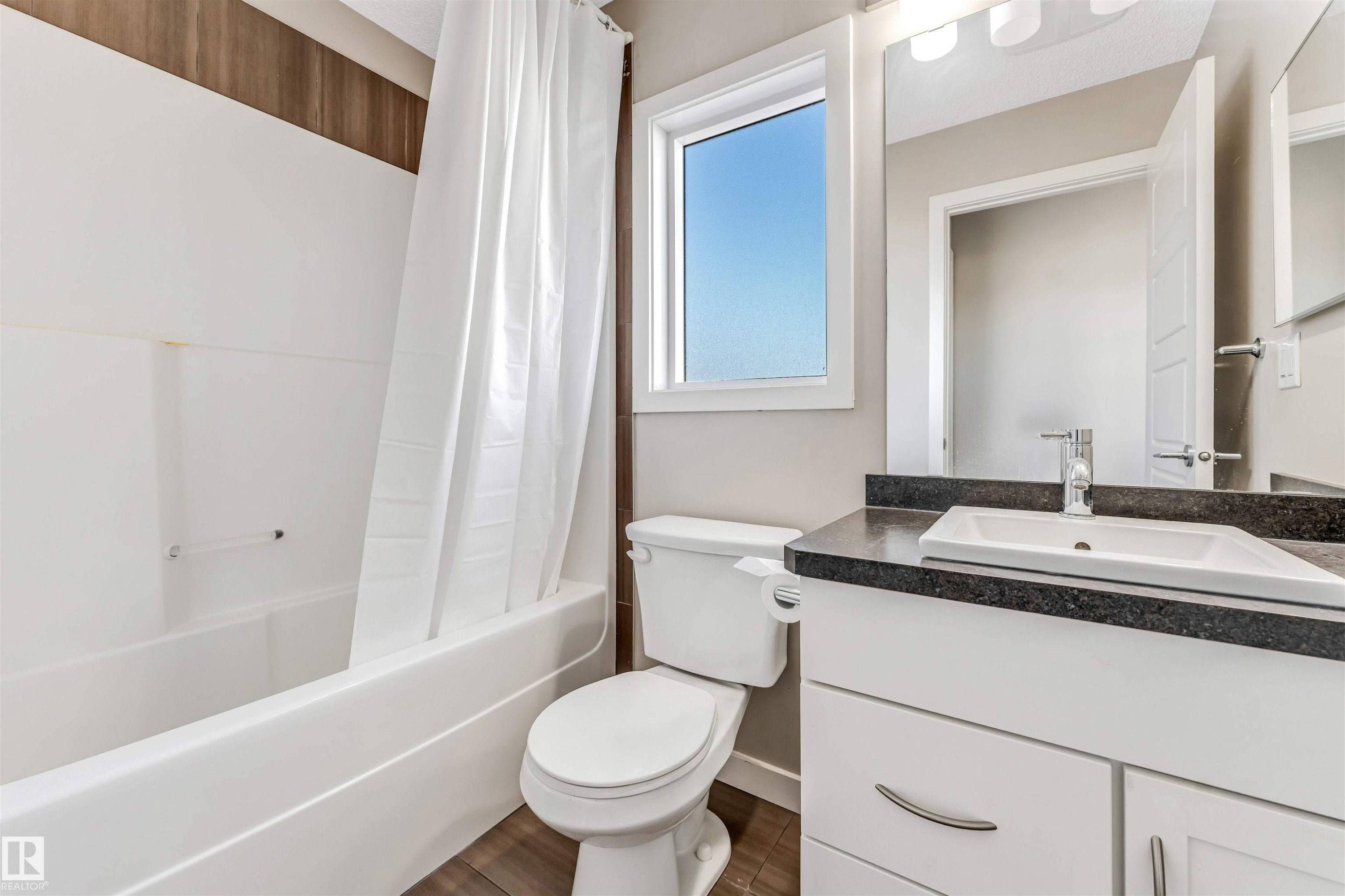 Bathroom featuring a white vanity with a dark countertop, an undermount sink, and chrome fixtures - 1624 33A Street, Edmonton, AB