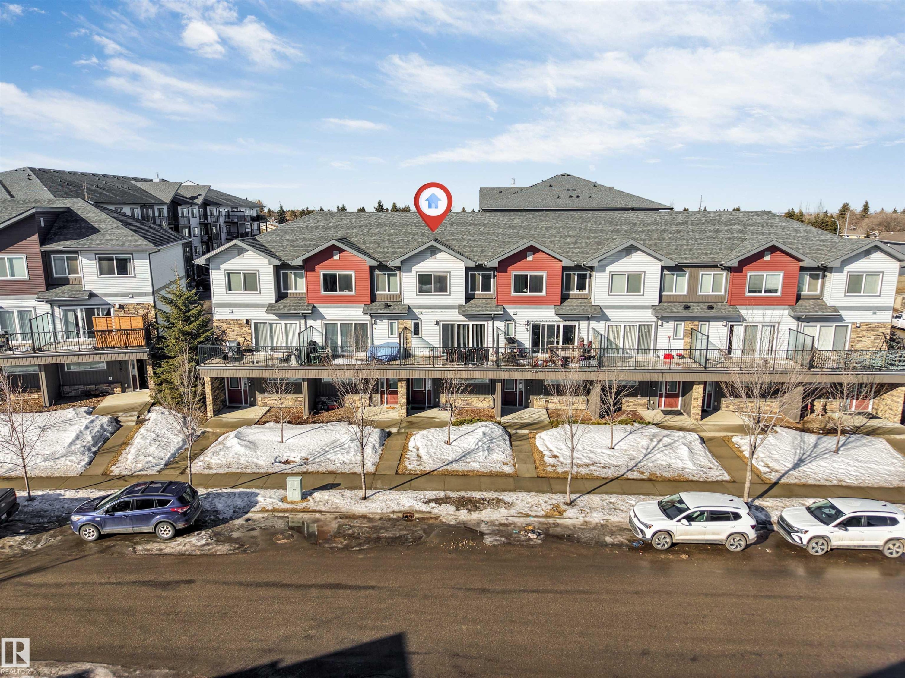 Contemporary townhome exterior featuring light siding, red accent panels, and gray shingle roofing - 1624 33A Street, Edmonton, AB
