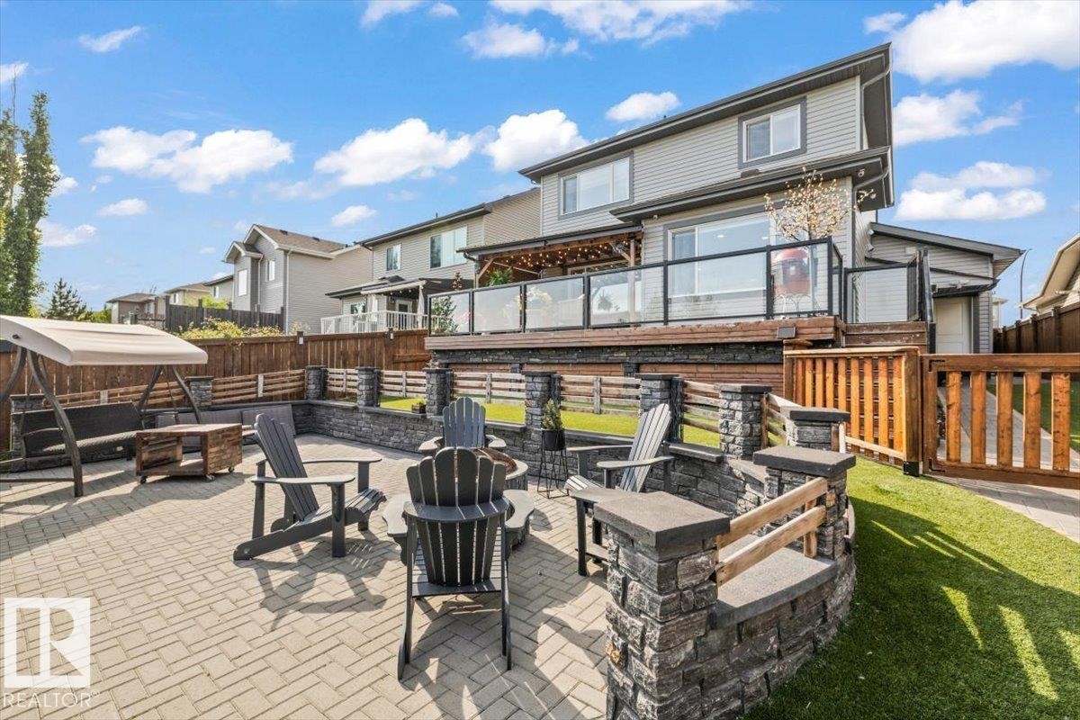 Expansive paver patio featuring a stone fire pit and a tiered stone retaining wall - 54 Spring Gate, Spruce Grove, AB