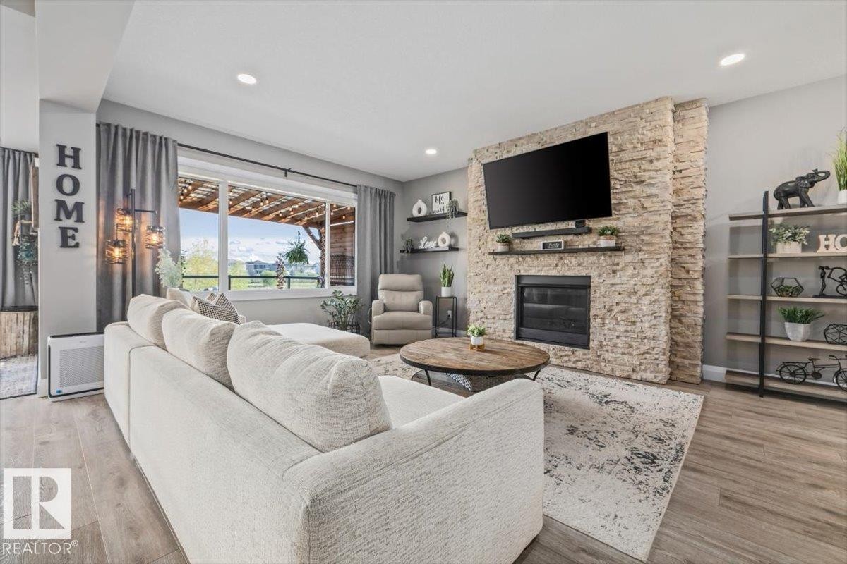 Living area featuring a floor-to-ceiling stacked stone fireplace, a large picture window, recessed lighting, and neutral palette - 54 Spring Gate, Spruce Grove, AB