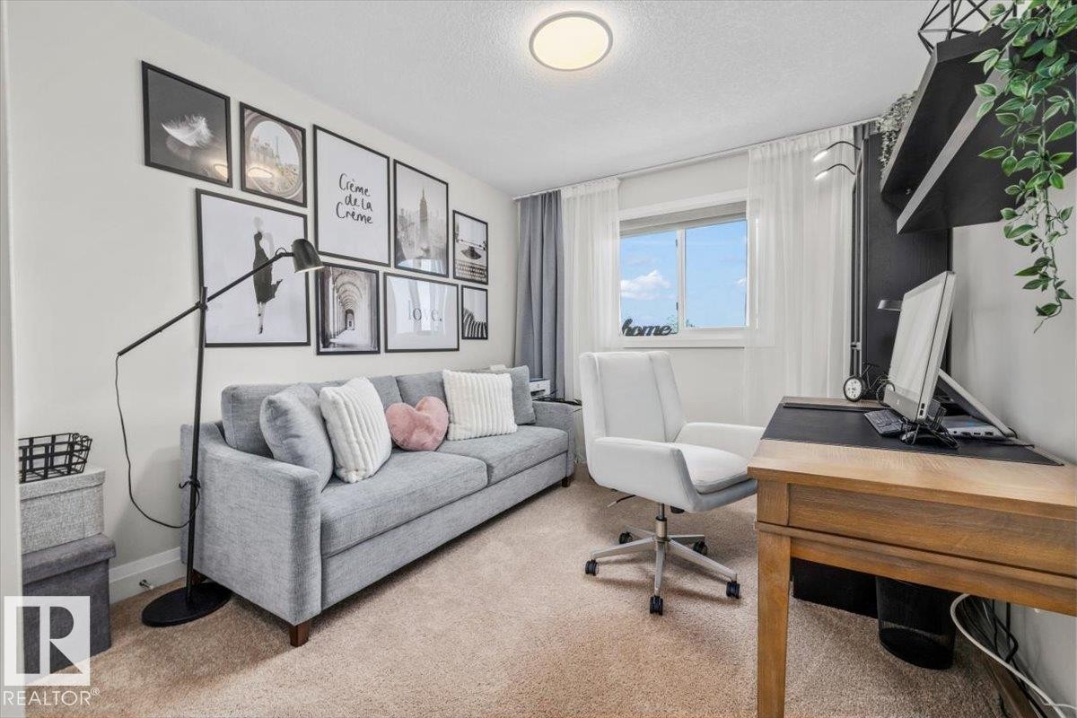 Carpeted room featuring a white window frame, white sheer curtains, and a built-in dark shelving unit - 54 Spring Gate, Spruce Grove, AB